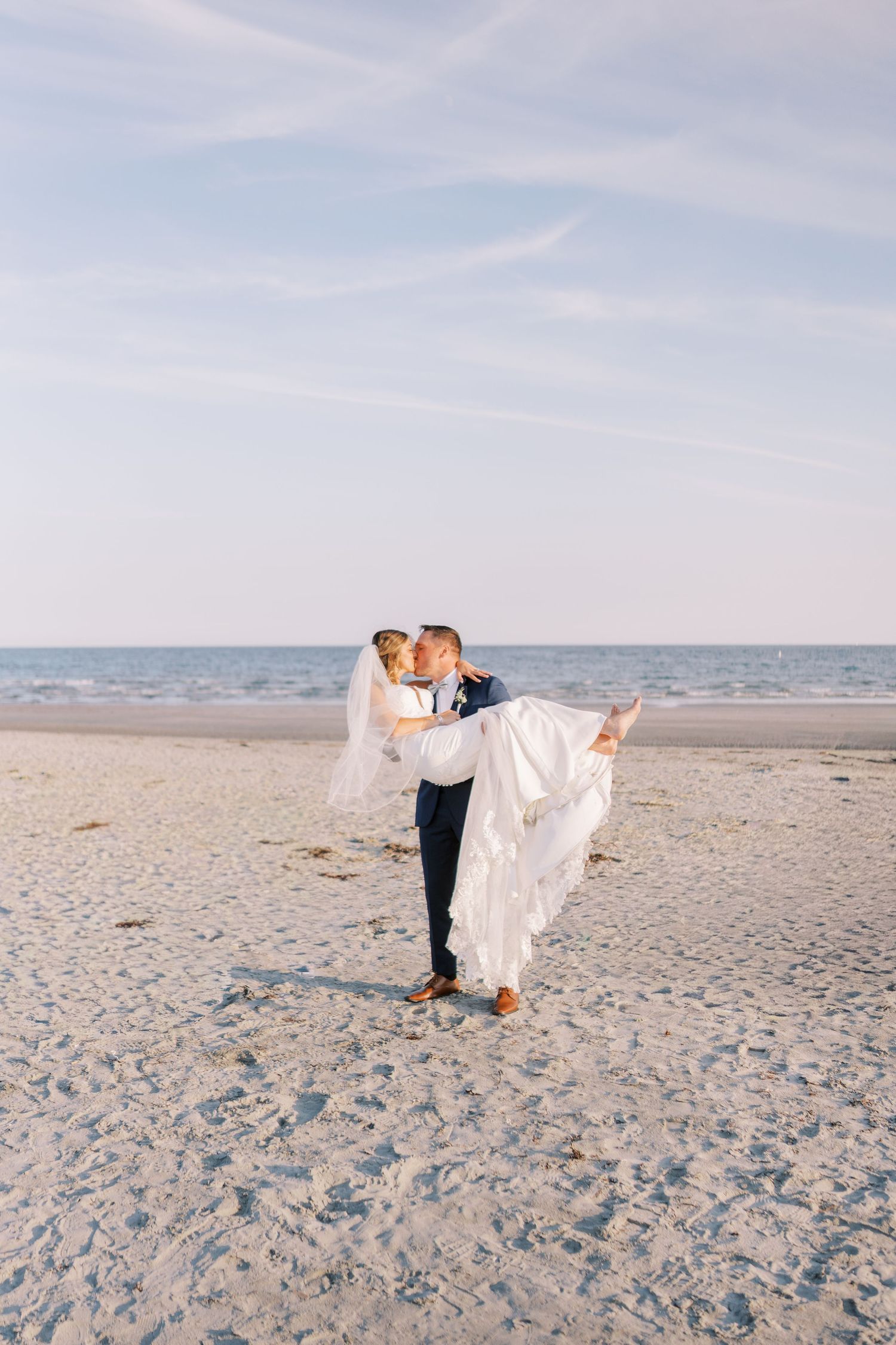 A romantic beach wedding scene with a couple embracing on sandy shores at sunset.