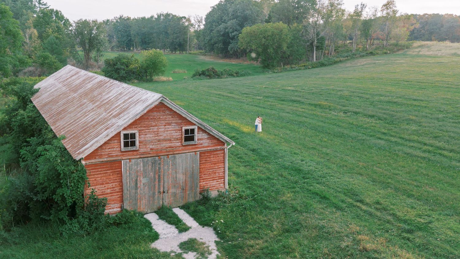A panoramic view of rural farmland with weathered red barns and green pastures stretching into the distance.