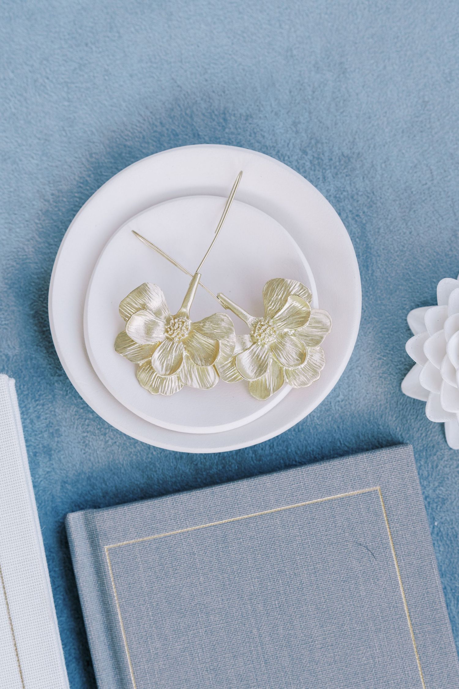 Delicate gold floral hair accessories displayed on white plate against blue background.