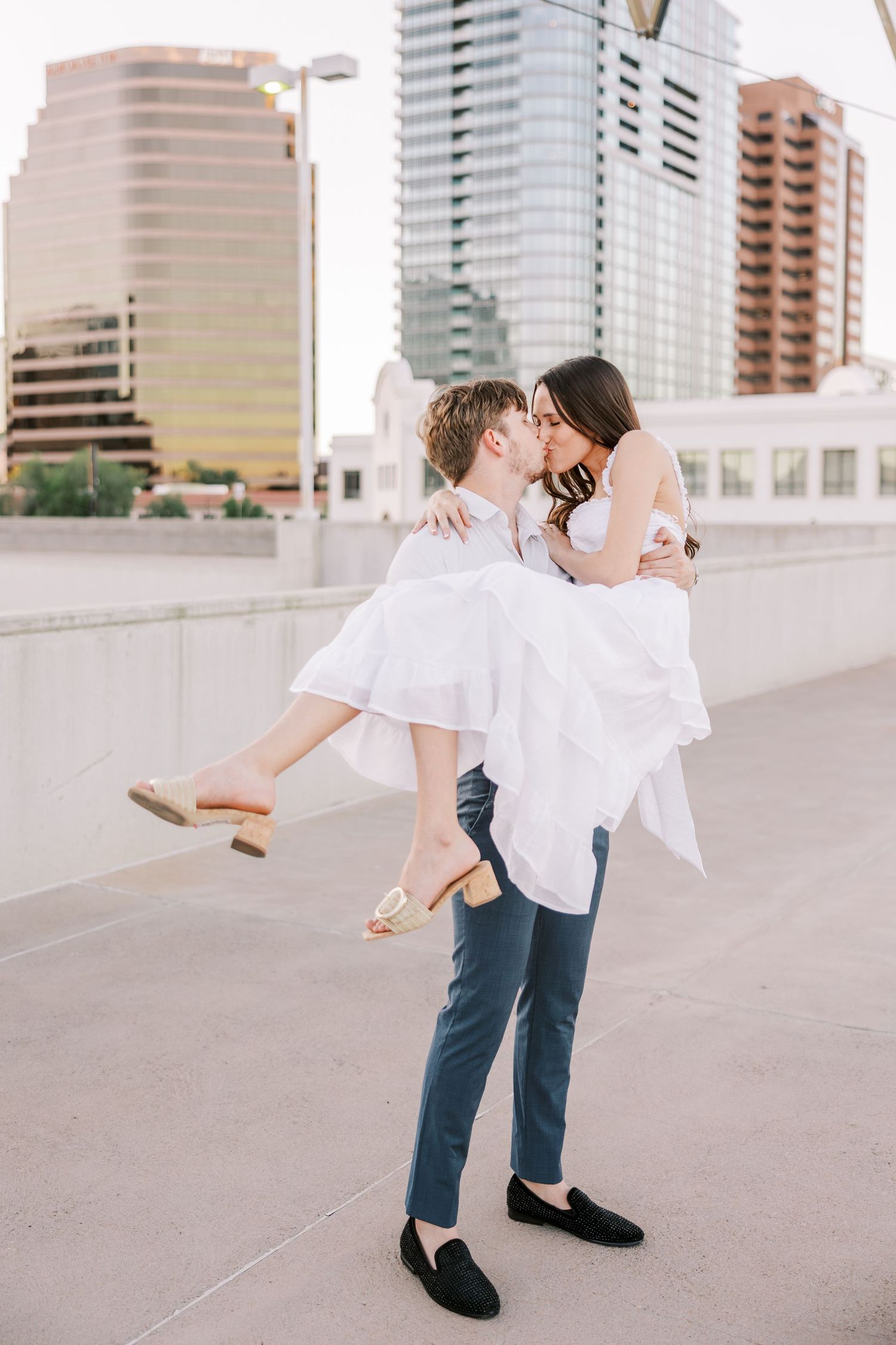 Playful dance lift pose on urban rooftop with high-rise buildings in background.