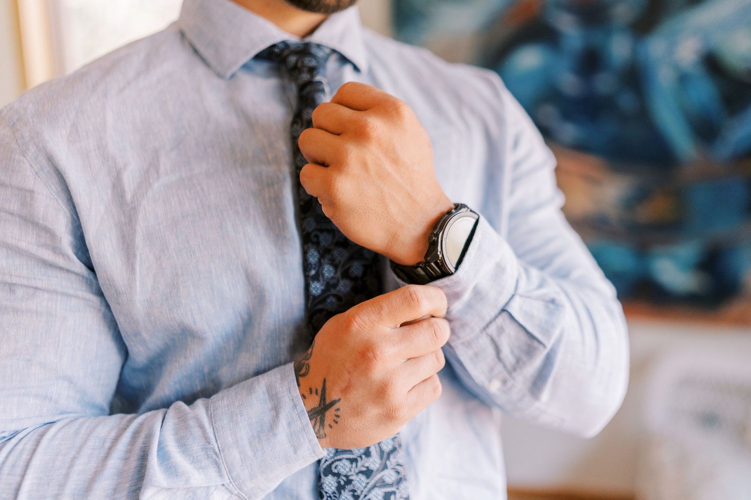 Close-up shots of someone adjusting a light blue dress shirt collar and cuffs in sequence.
