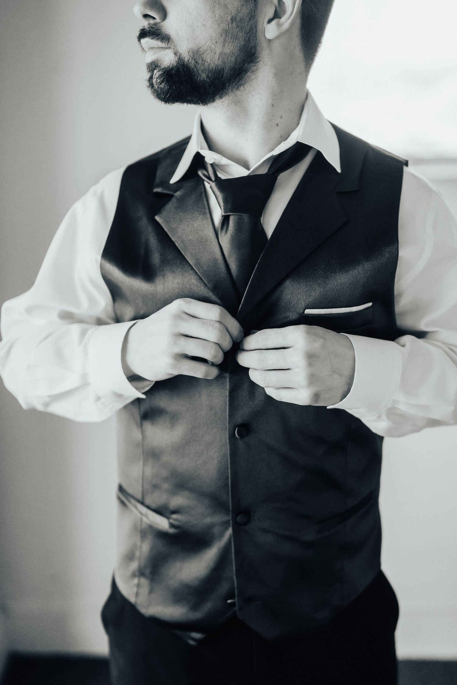 Close-up sequence of someone adjusting a formal dark vest over a white dress shirt.