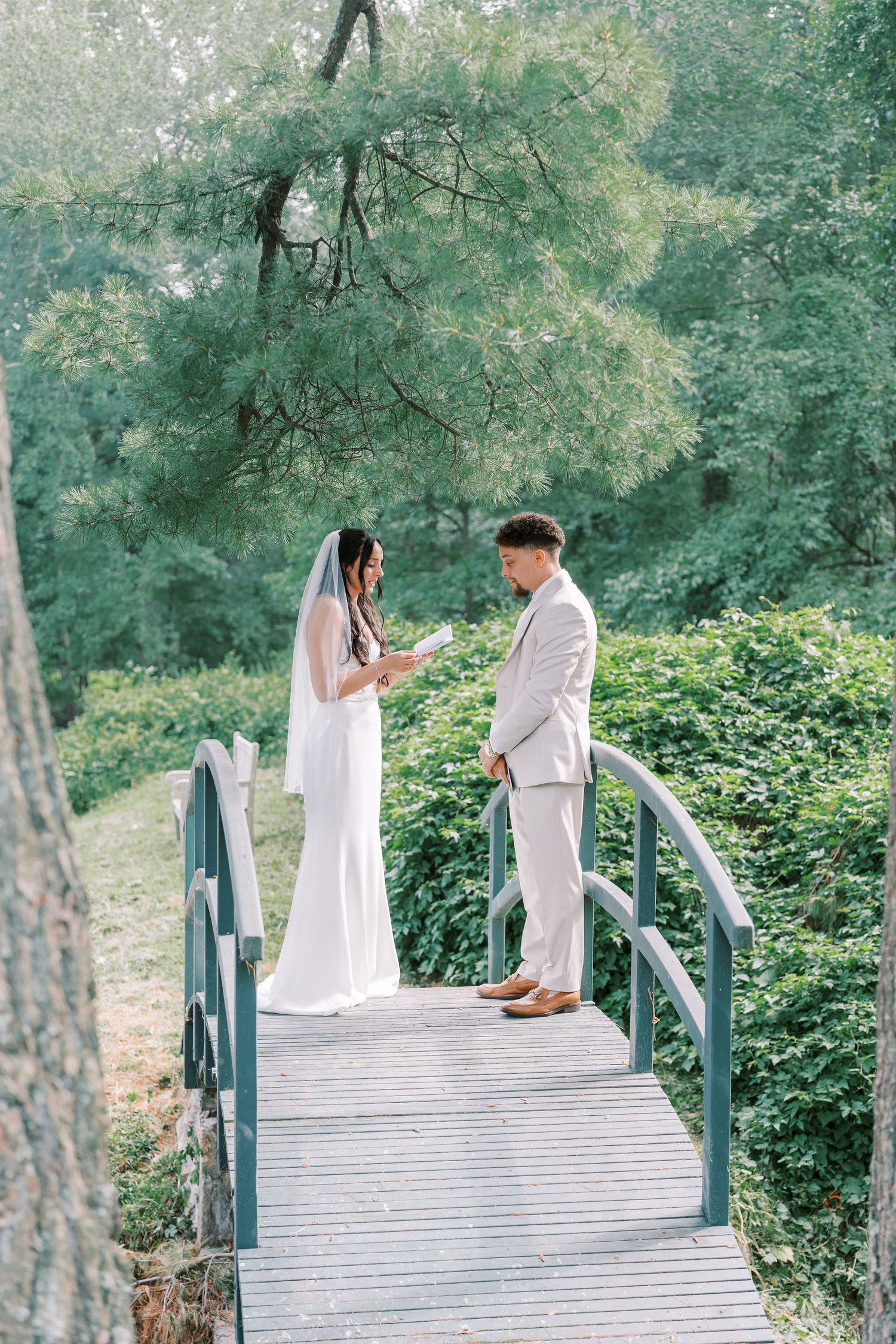 Couple sharing a private moment on a wooden bridge surrounded by lush greenery.
