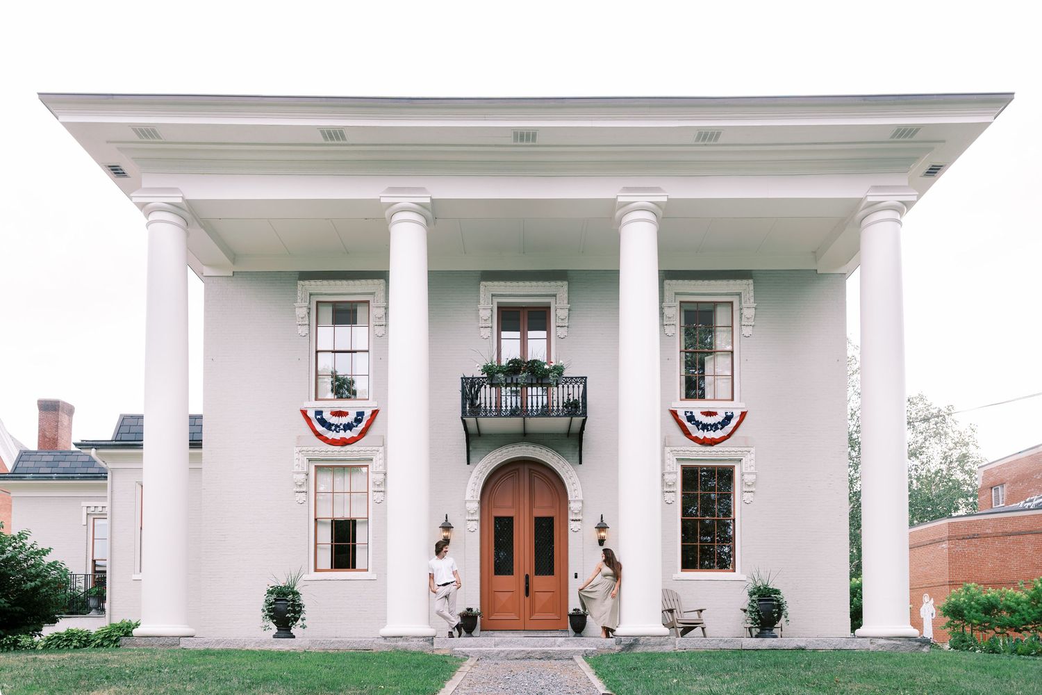 White colonial-style house with grand pillared porch and symmetrical windows in a classic American architectural design.