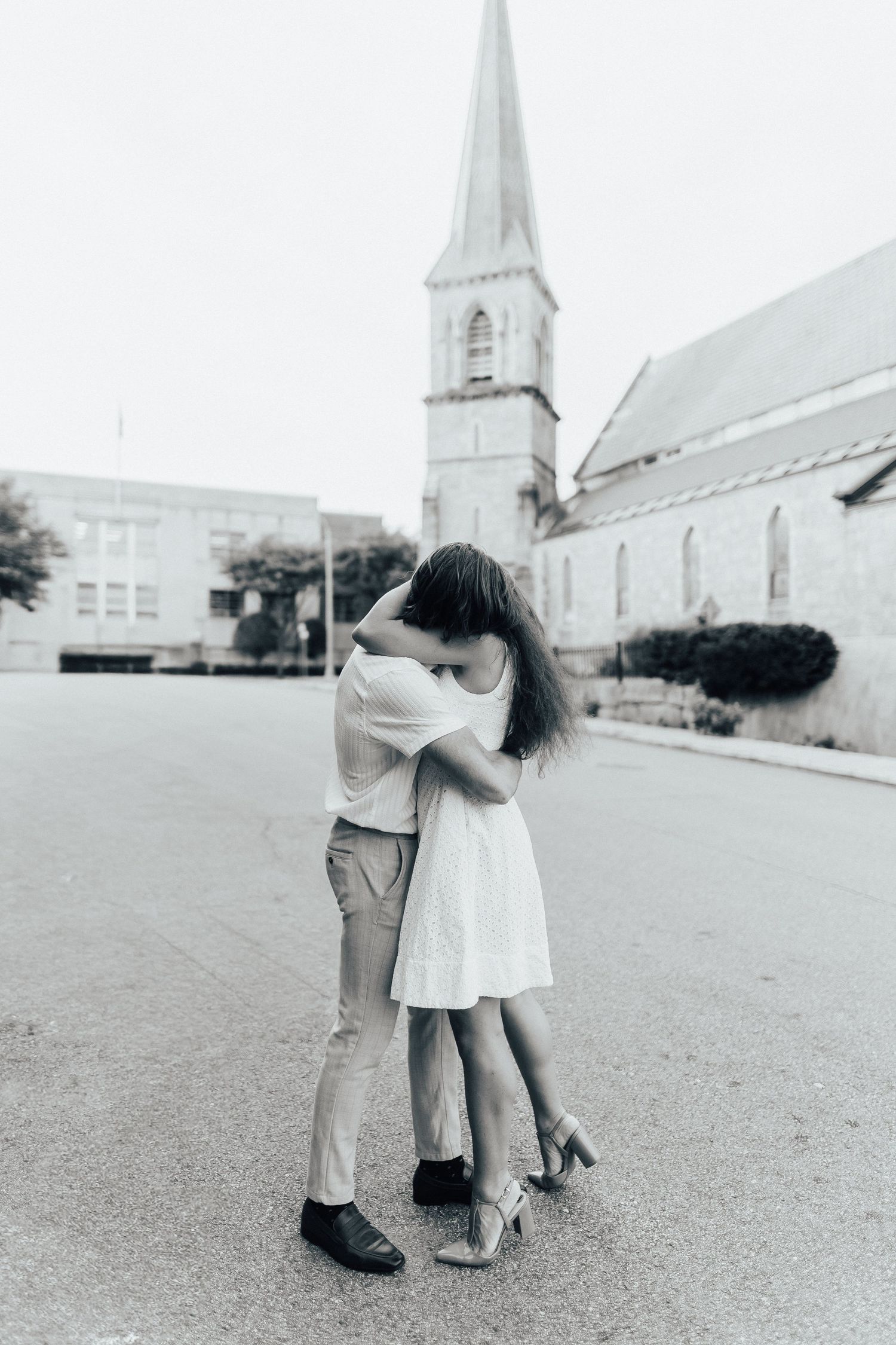 Black and white sequence shows a couple dancing in an open space with a church spire in the background.