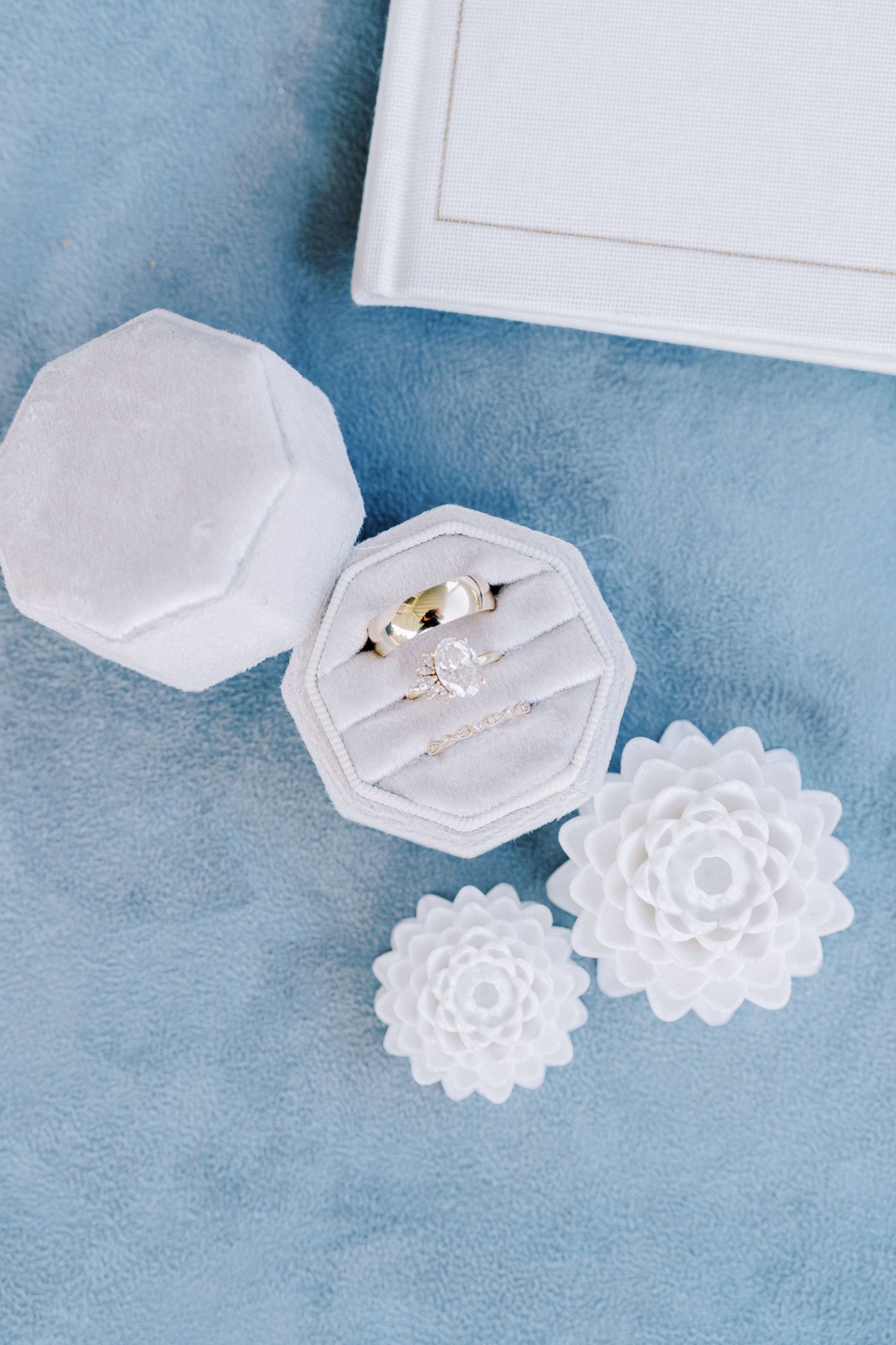 White hexagonal ring boxes with floral designs on blue textured background.