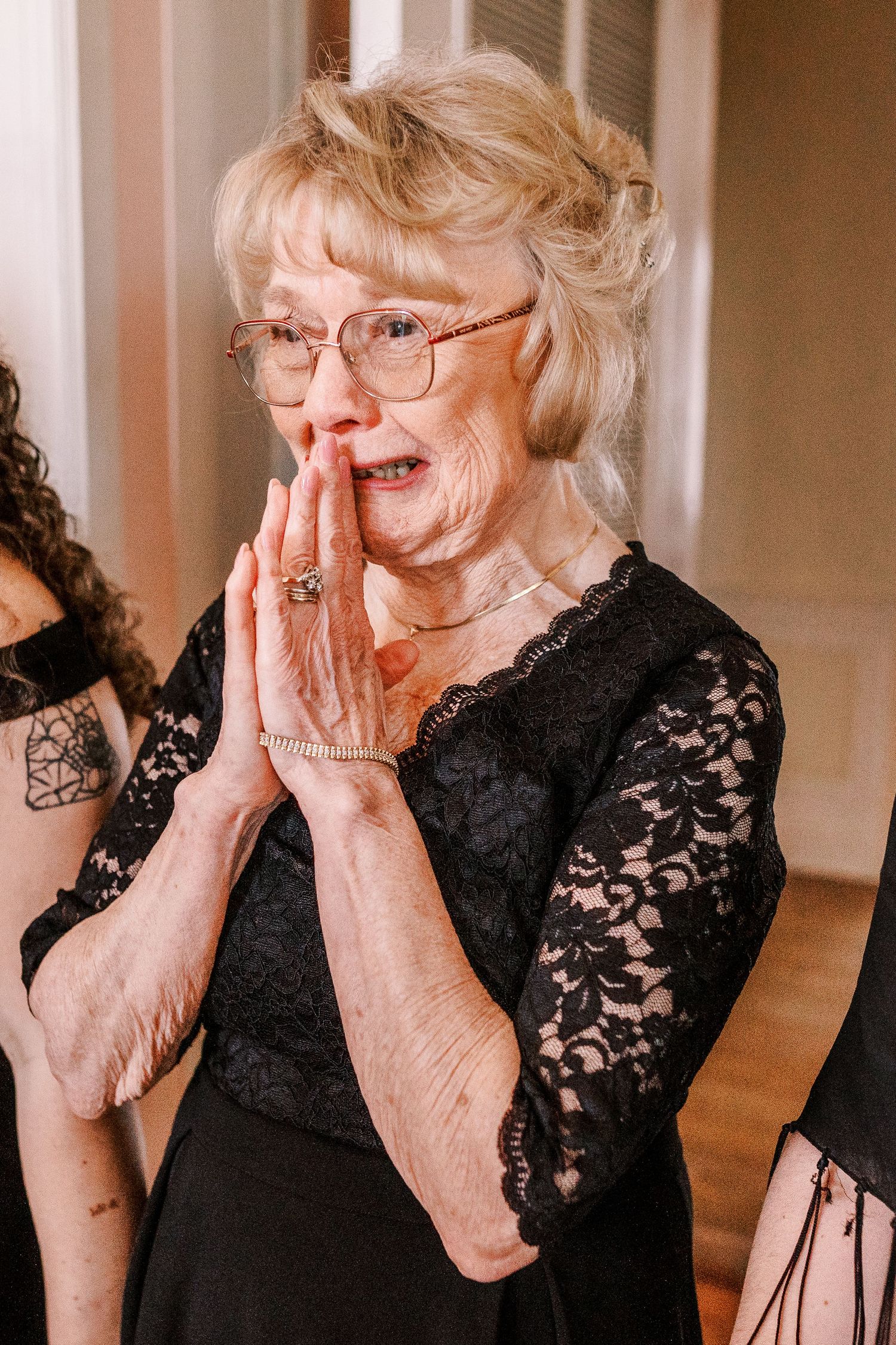 An emotional moment captured as someone wearing a black lace dress covers their face during a wedding celebration.