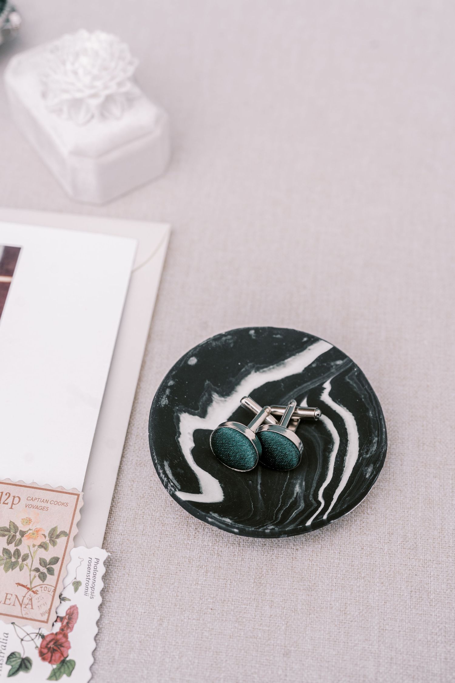 Turquoise earrings displayed on a black and white marbled decorative plate next to paper and white box.