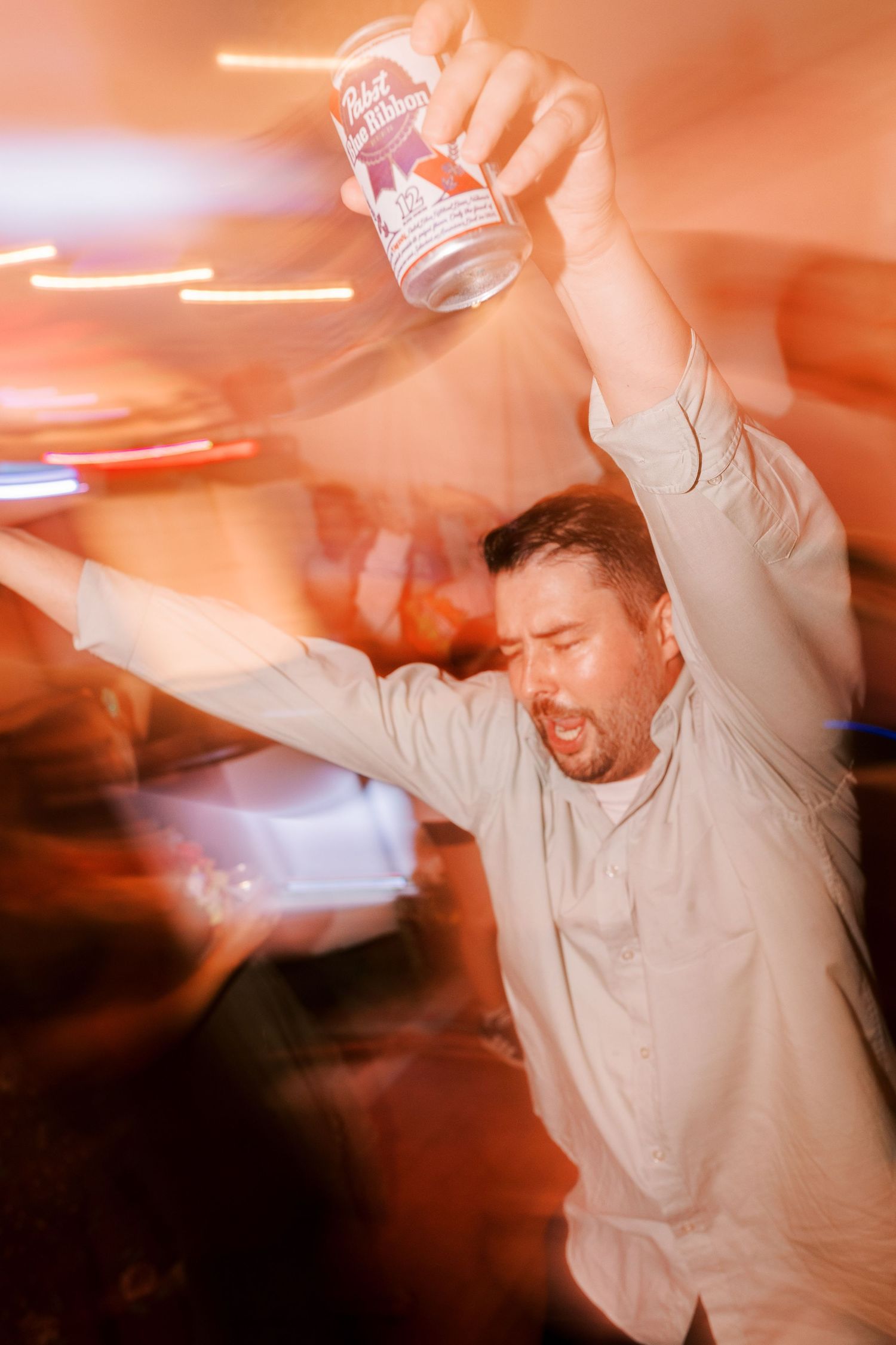 Motion-blurred party scene with orange lighting and celebratory dancing.