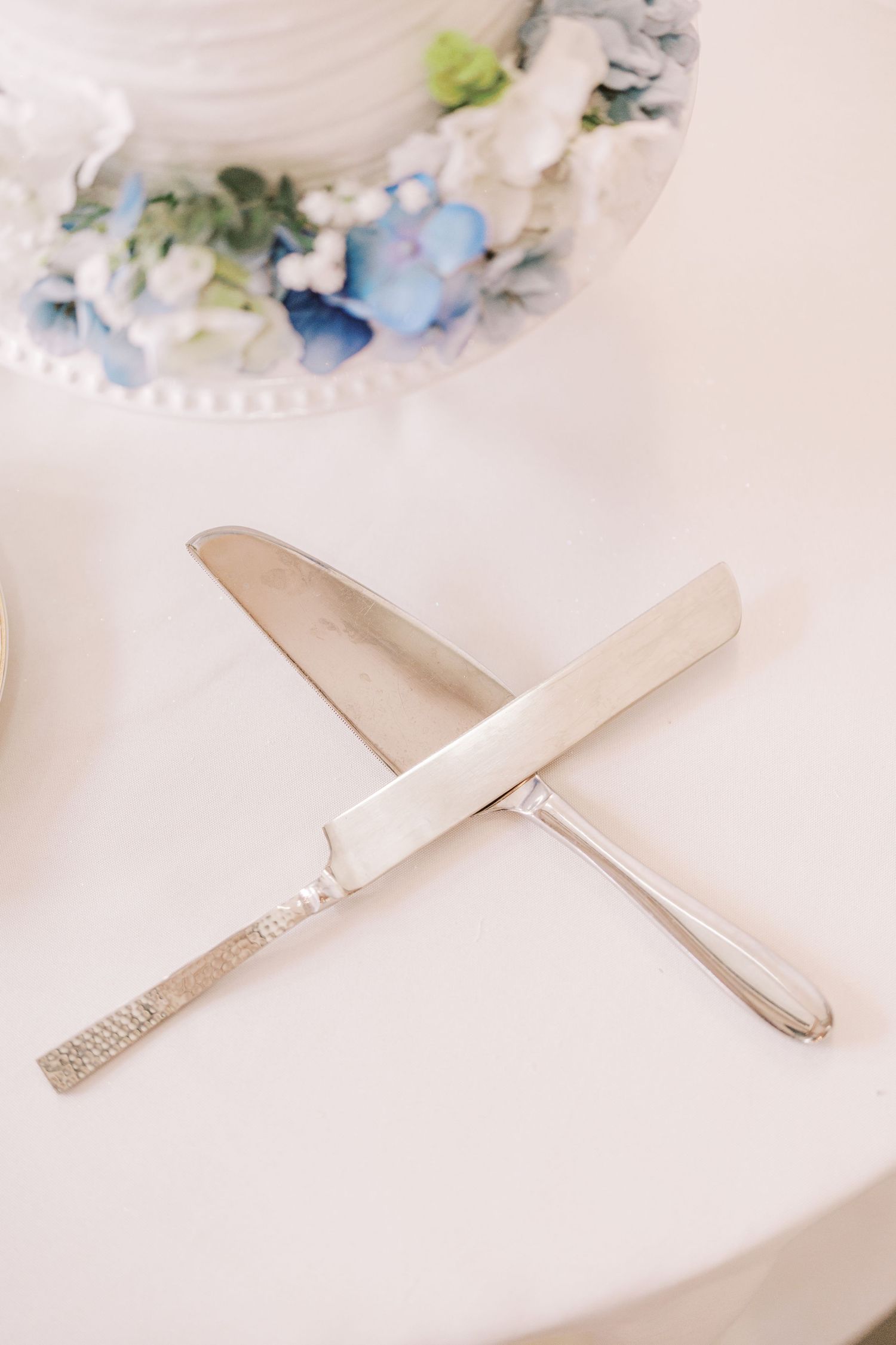 Delicate white and blue floral arrangements displayed alongside elegant silver cutlery on a light background.
