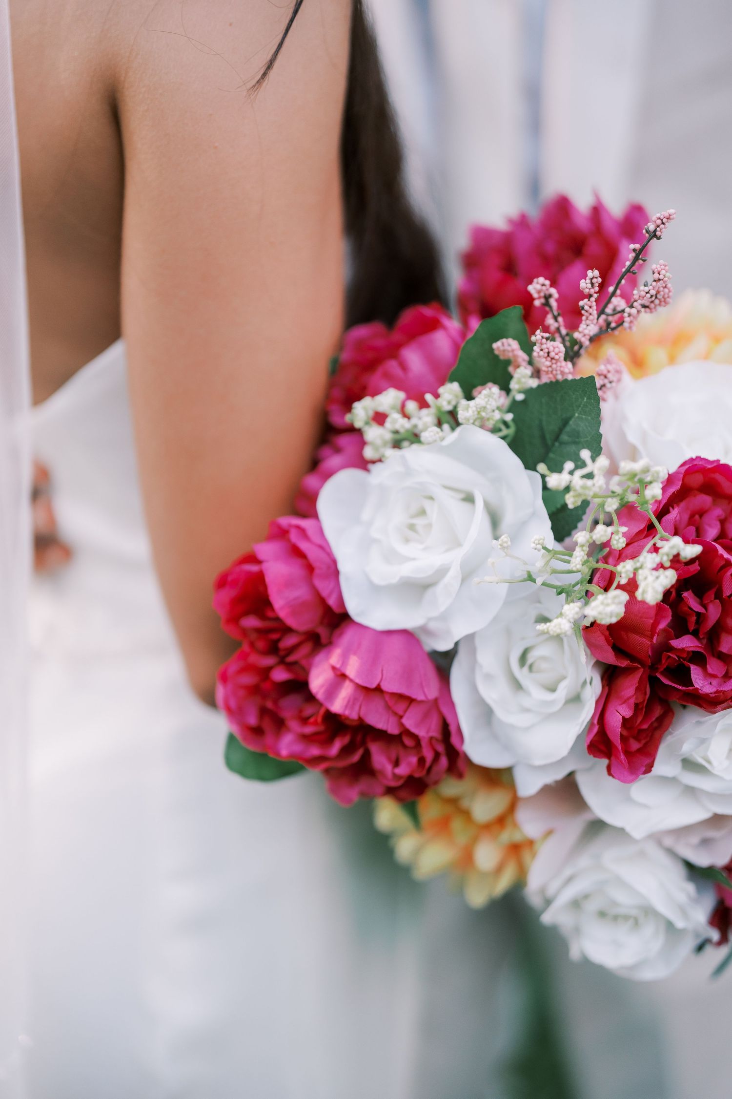 Close-up of bridal bouquet with pink and white roses against white wedding dress.