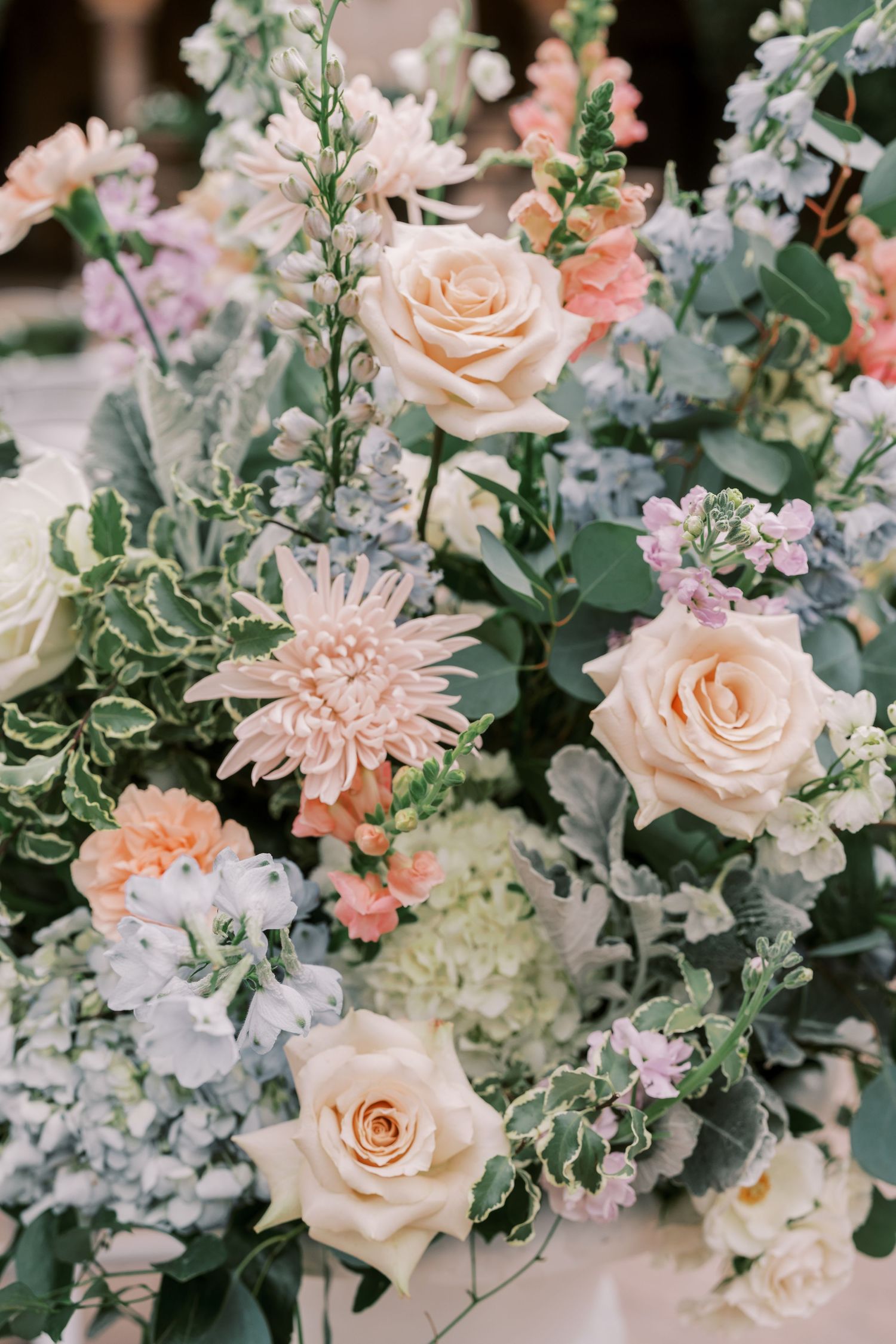 Elegant floral arrangement featuring peach roses, dahlias and delicate white blooms with soft green foliage.