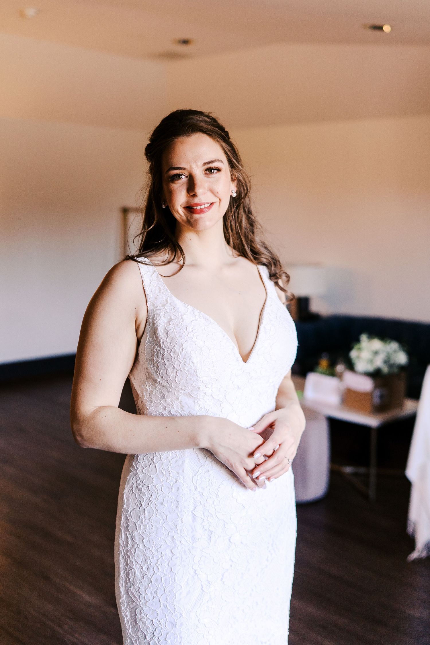 Close-up details of a beautiful white lace wedding dress in an indoor setting.