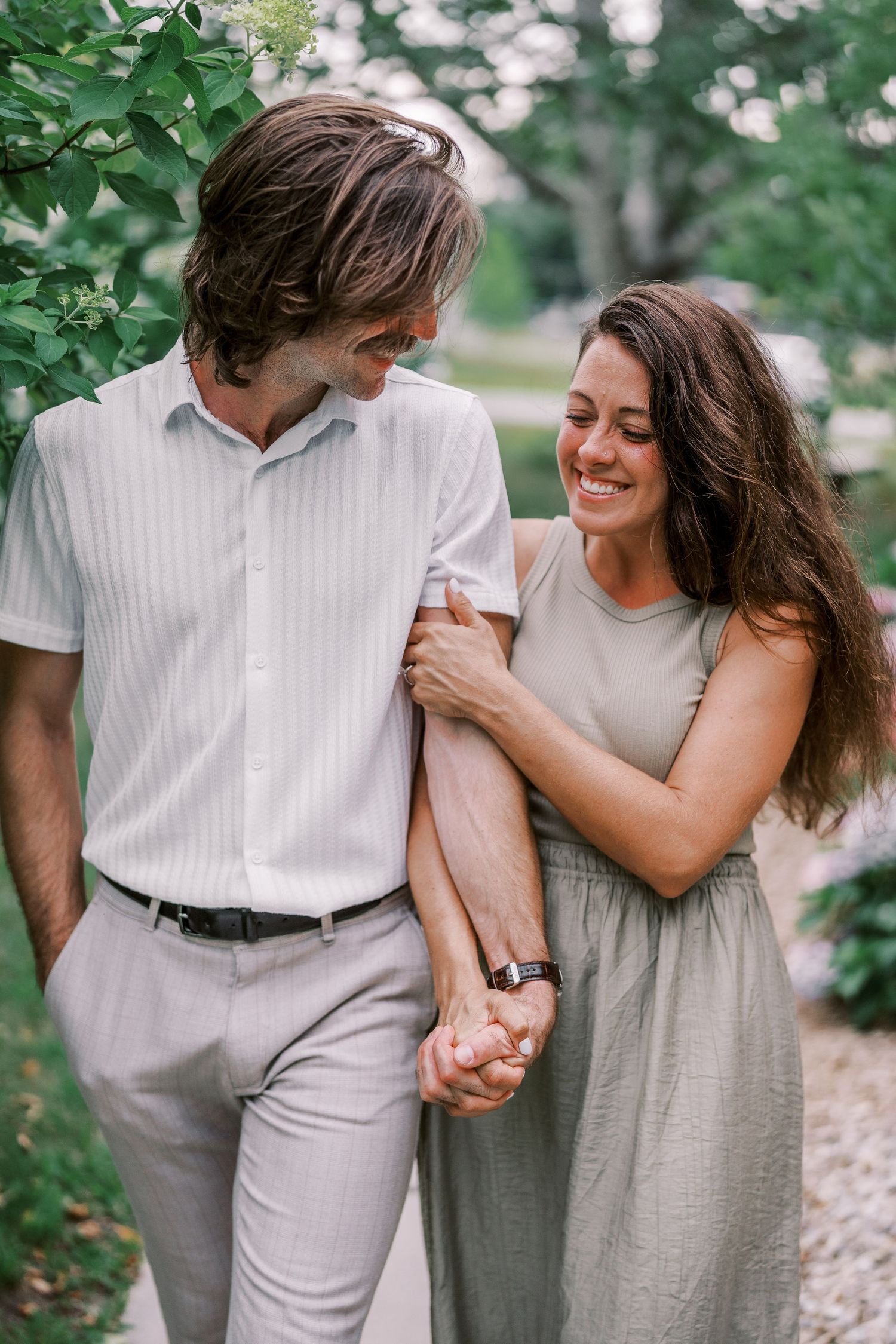 Sweet candid moments of a couple walking hand-in-hand through a lush garden path.