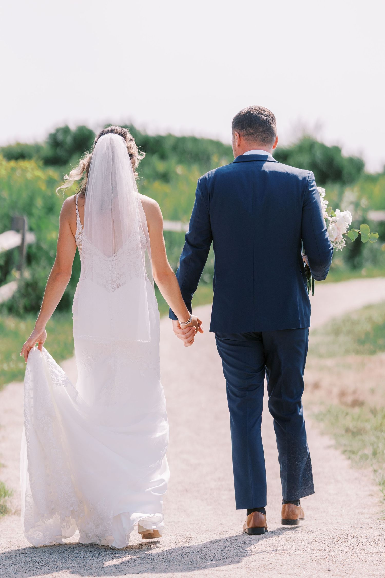 Wedding couple walks hand in hand down a dirt path in a sequence of romantic shots from behind.