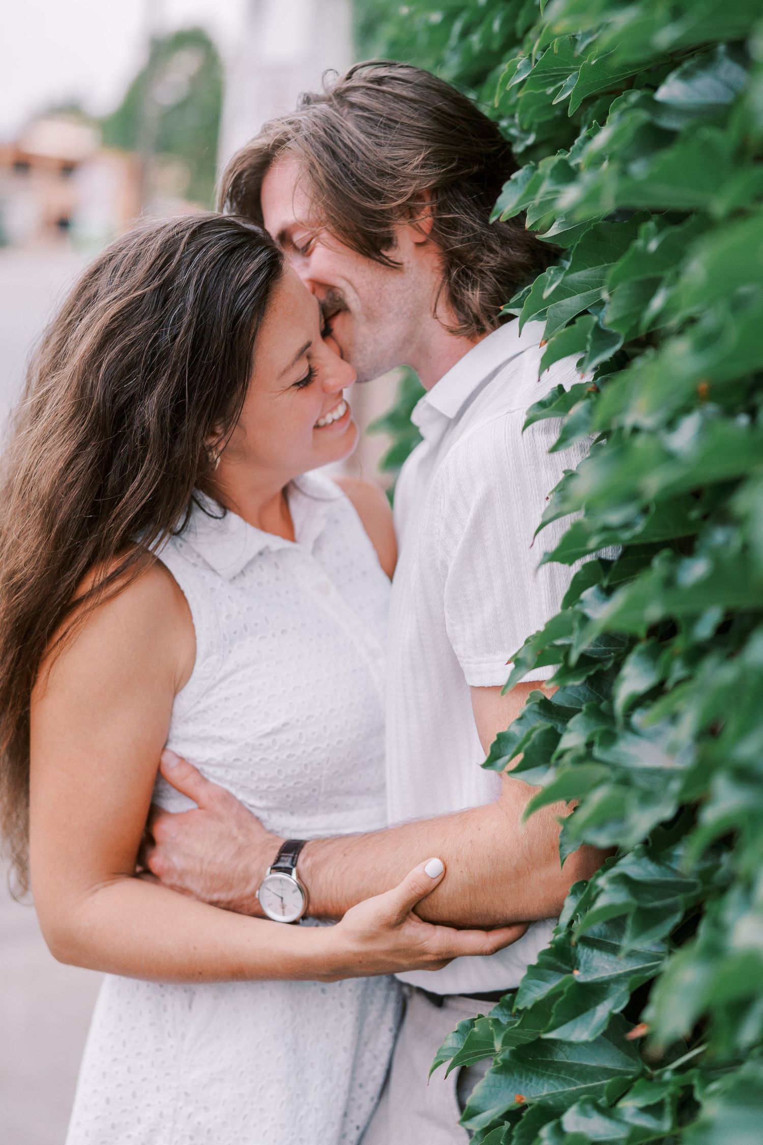 Intimate moment shared between couple among green ivy covered wall.