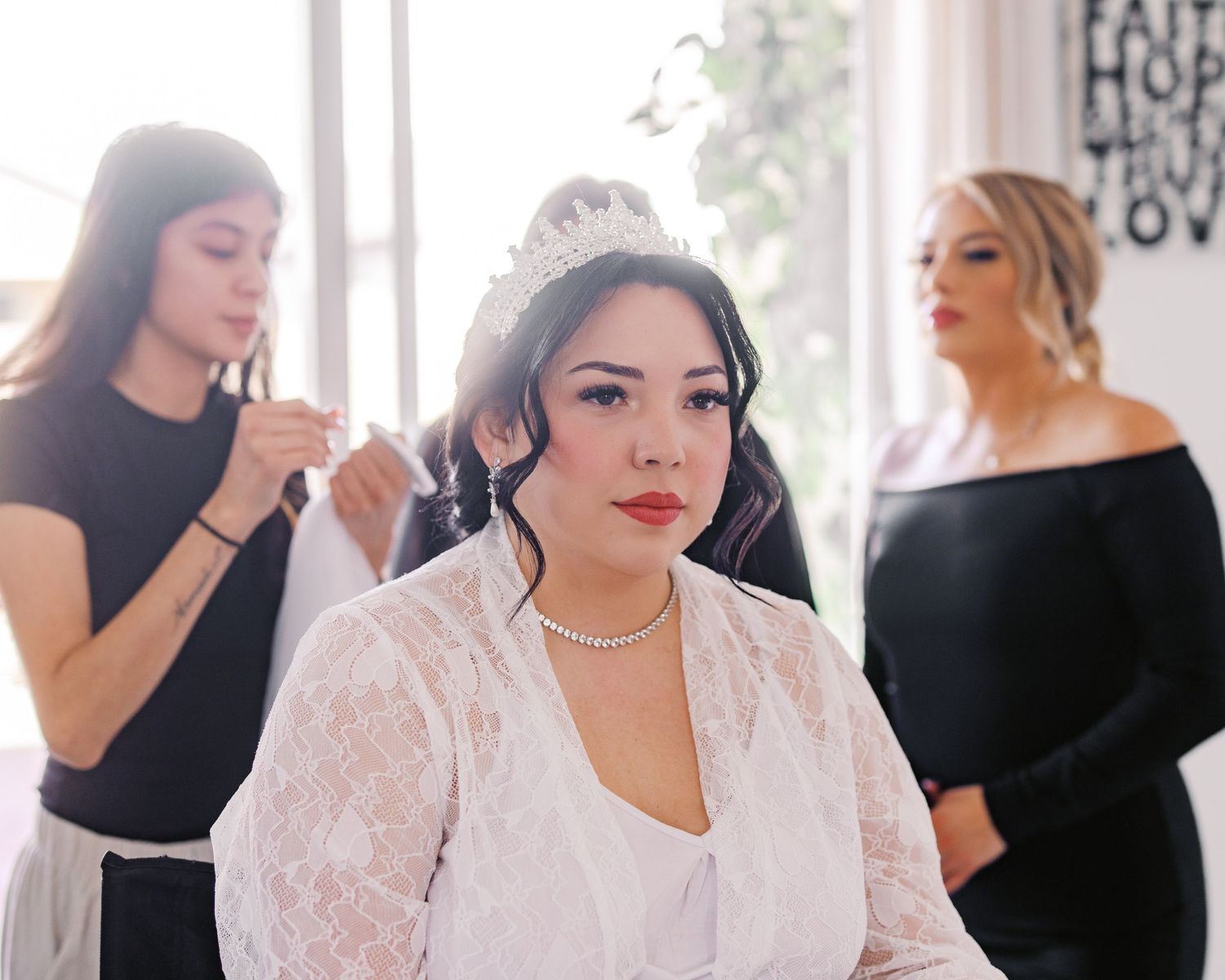 Wedding preparations in progress with bride in white lace robe getting final touches done before the ceremony.