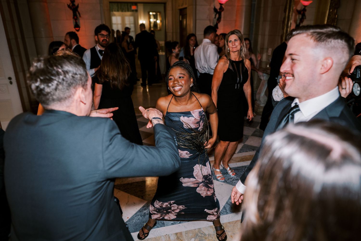Wedding reception guests dancing and celebrating in a dimly lit venue.