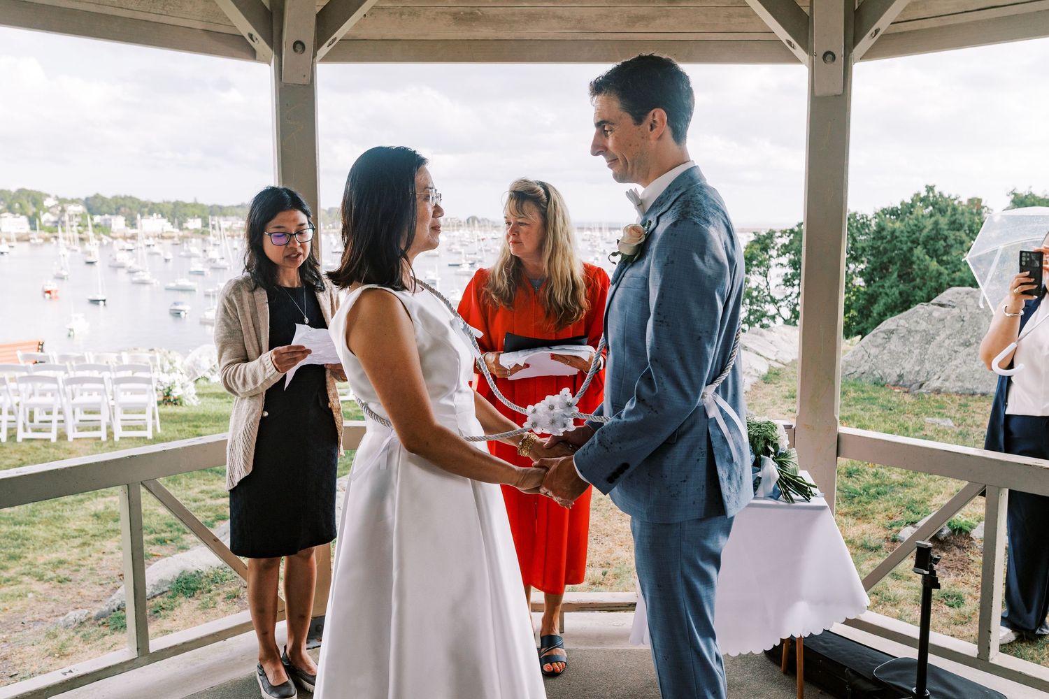 Wedding attendees mingling under an outdoor pavilion during a waterfront celebration.