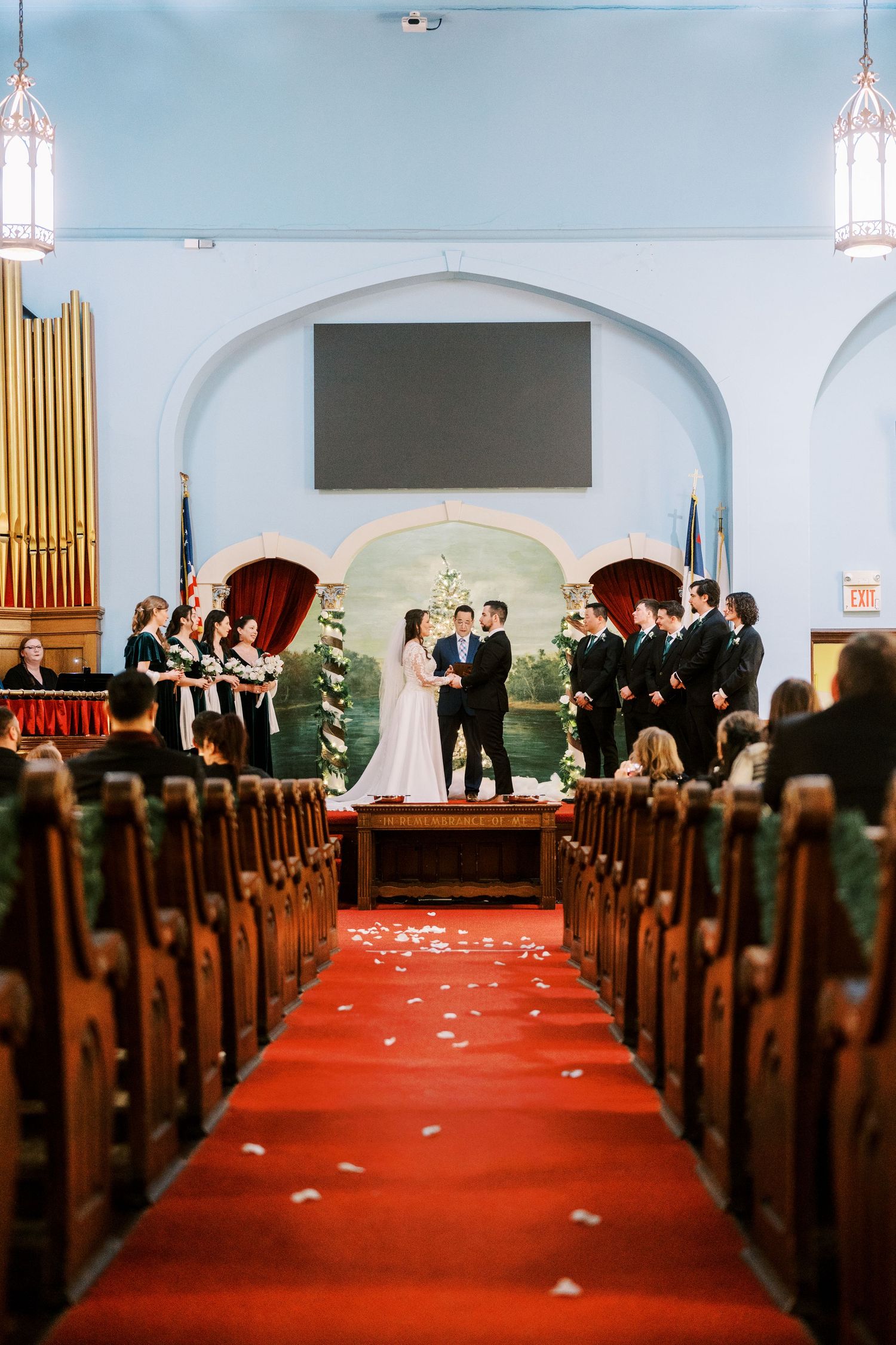 A traditional church wedding ceremony with red carpet aisle and wooden pews.