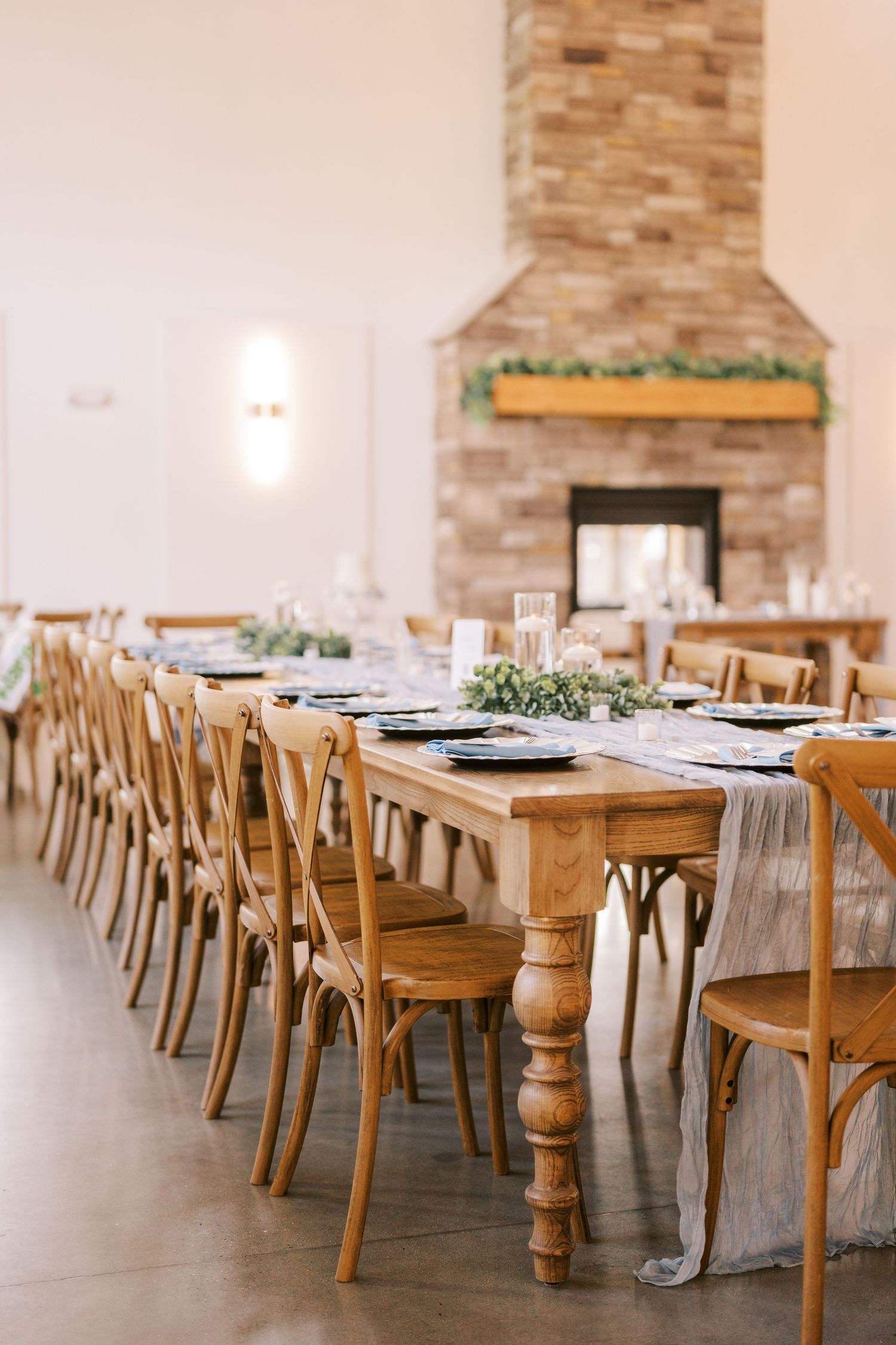 Elegant wedding reception venue with wooden tables, gray linens, and exposed brick walls creating a rustic atmosphere.