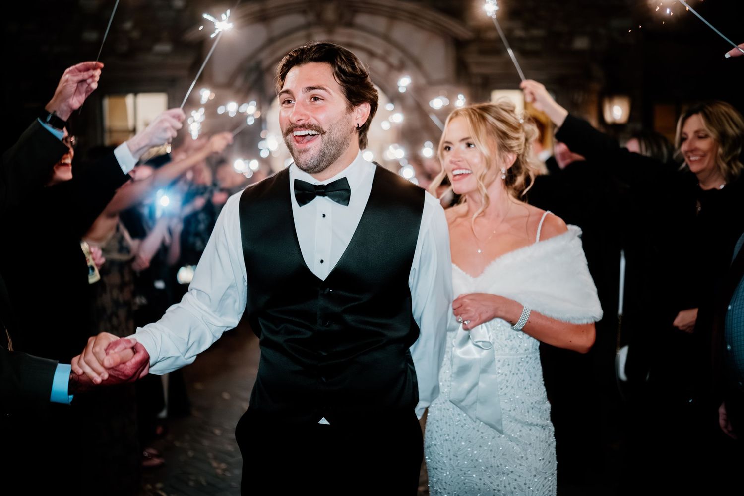 Newlyweds dance joyfully together surrounded by guests throwing confetti during their wedding reception celebration.
