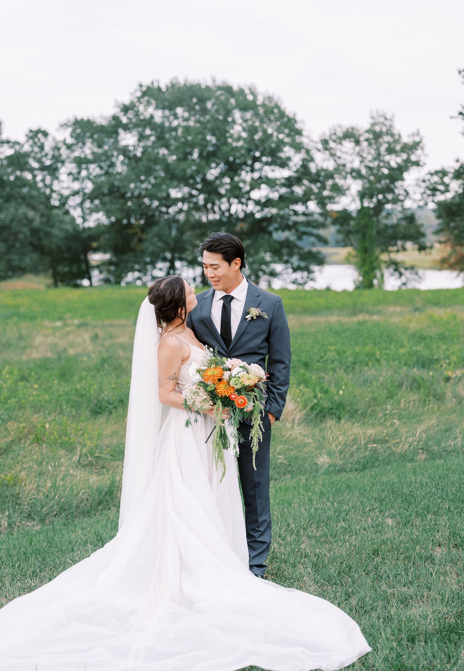Romantic outdoor wedding portraits on a grassy hillside with flowing white veil.