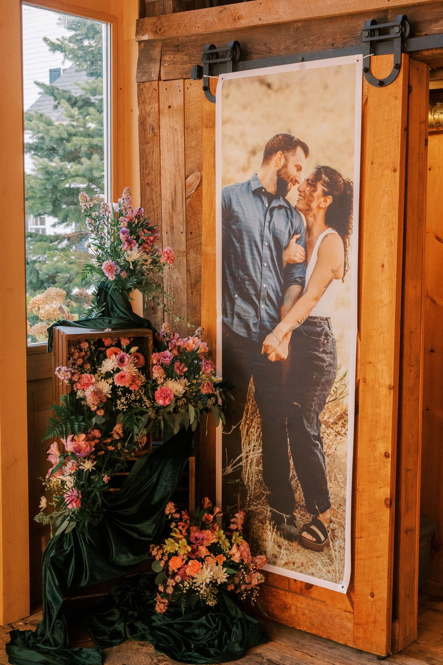 Romantic portrait display with pink floral arrangements against rustic wooden barn door decor.