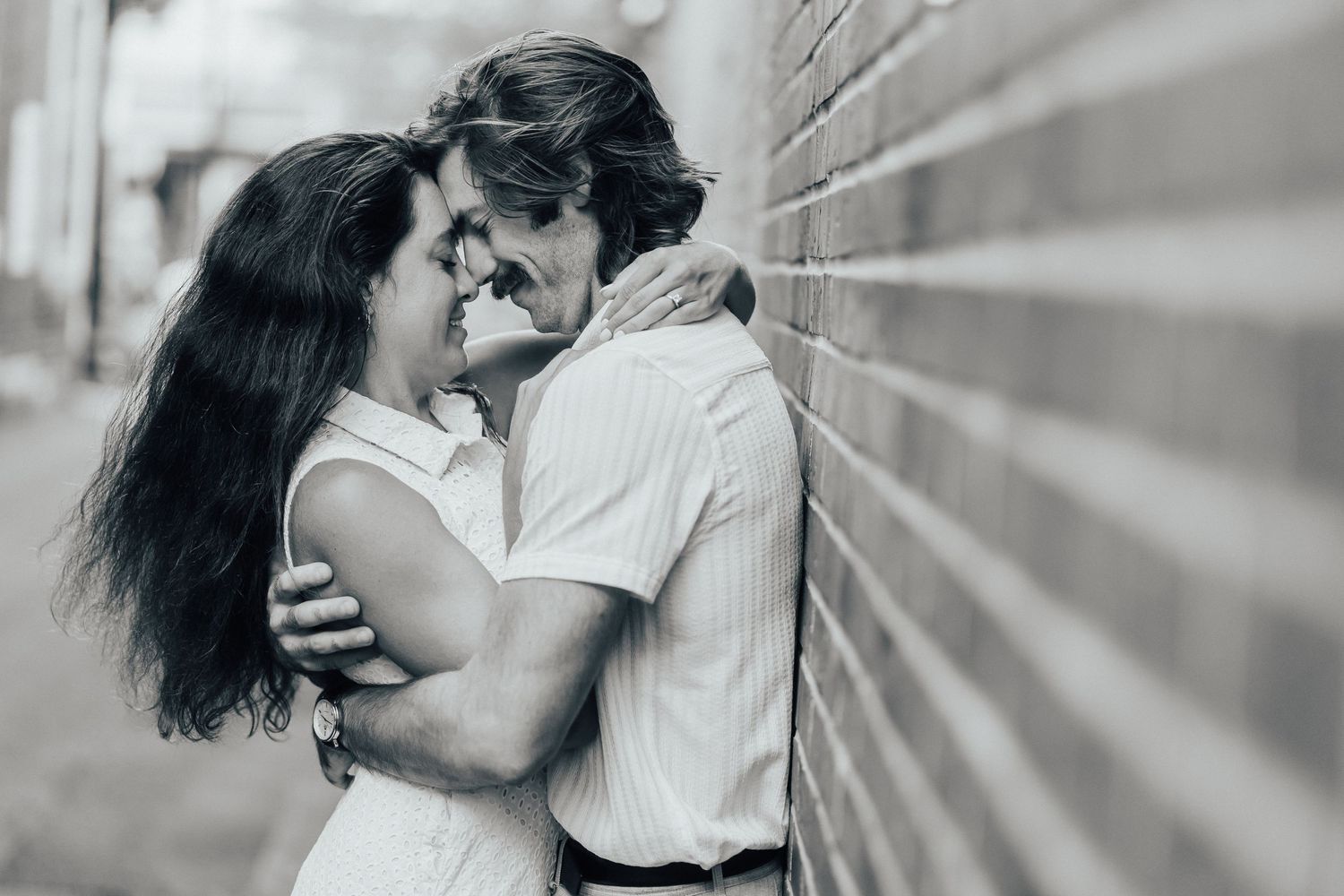 Black and white romantic sequence of a couple dancing intimately near a brick wall.