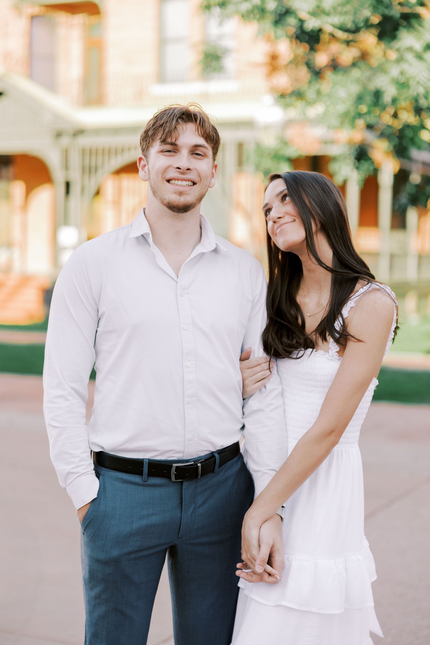 Couple in coordinated white and navy outfits sharing playful moments during an outdoor photoshoot.