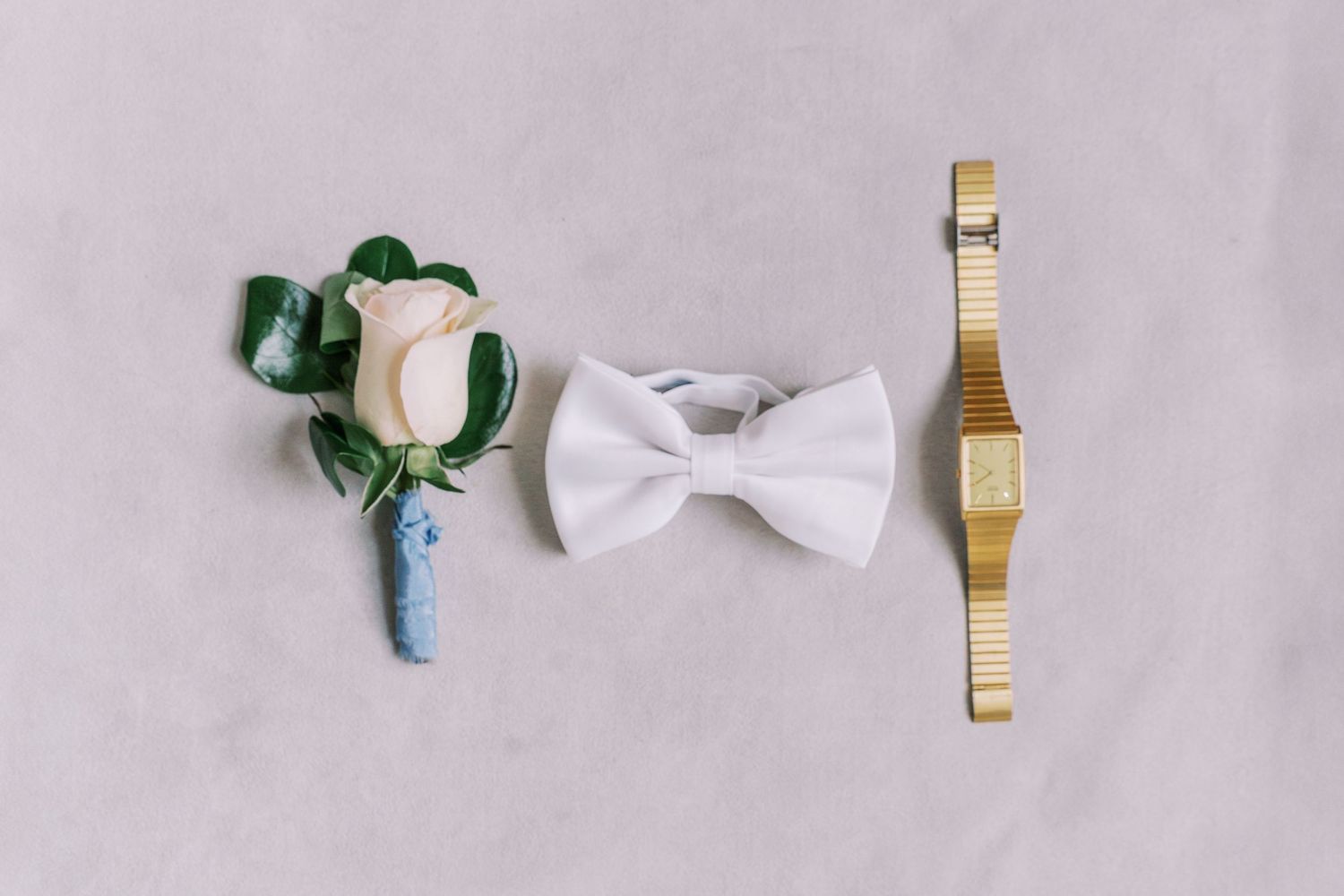 White satin bows and decorative elements arranged with gold accents on a pastel pink background.