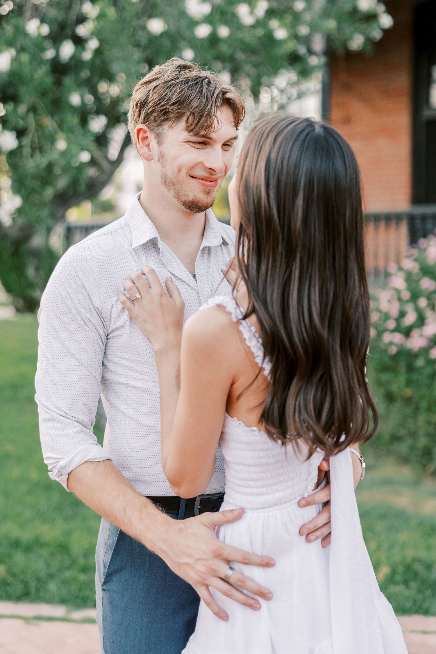 Couple sharing intimate moments in a garden setting with blooming flowers and greenery.
