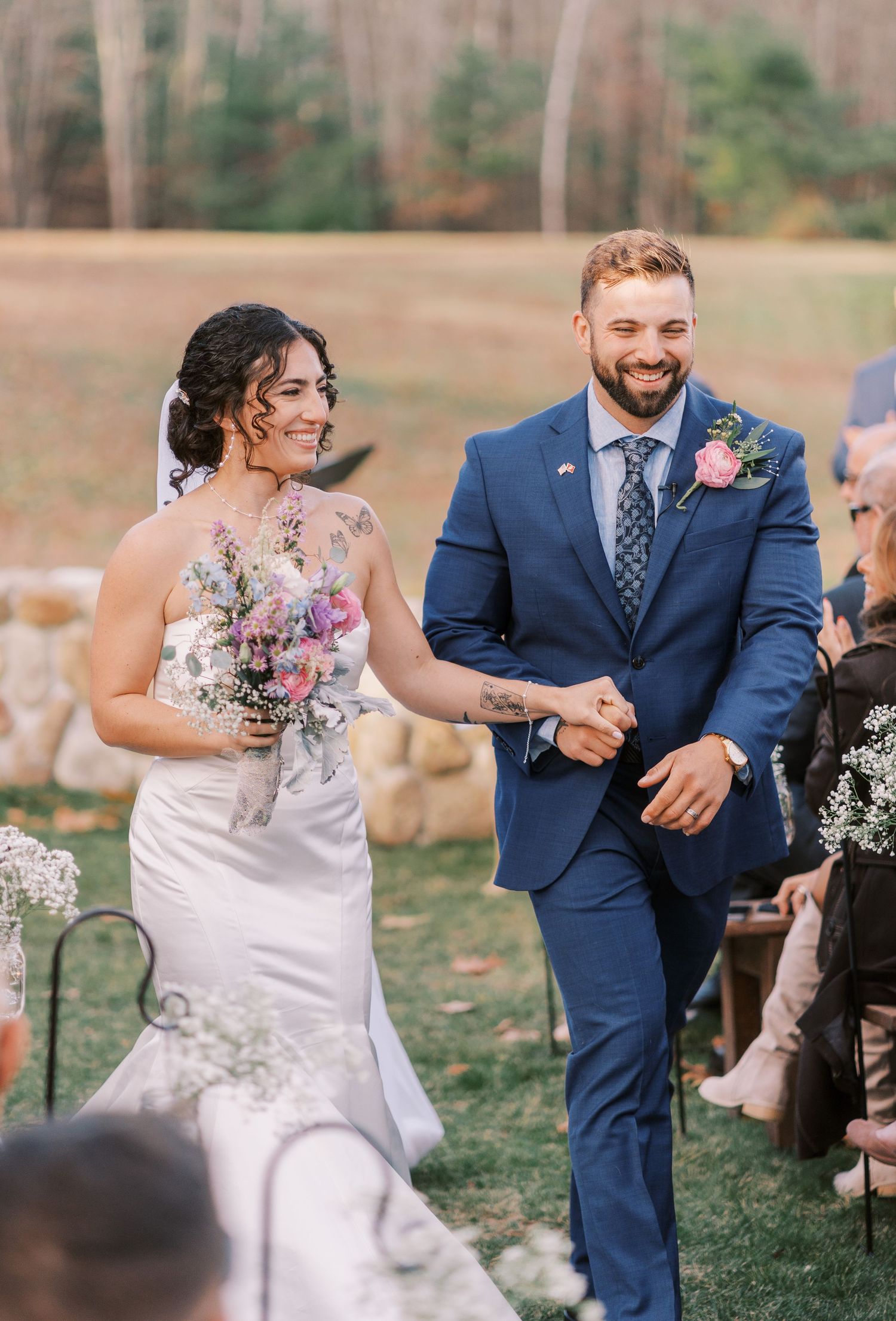 A couple in wedding attire share a joyful moment dancing together outdoors during their celebration.