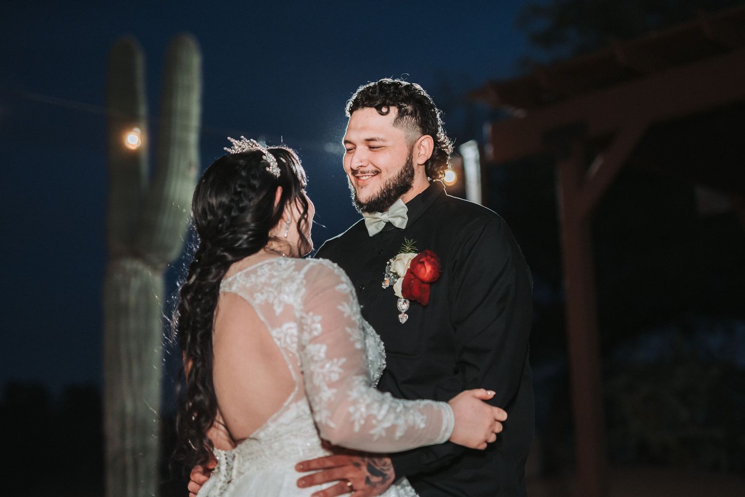 A couple shares their first dance moment at dusk outdoors during their wedding celebration.