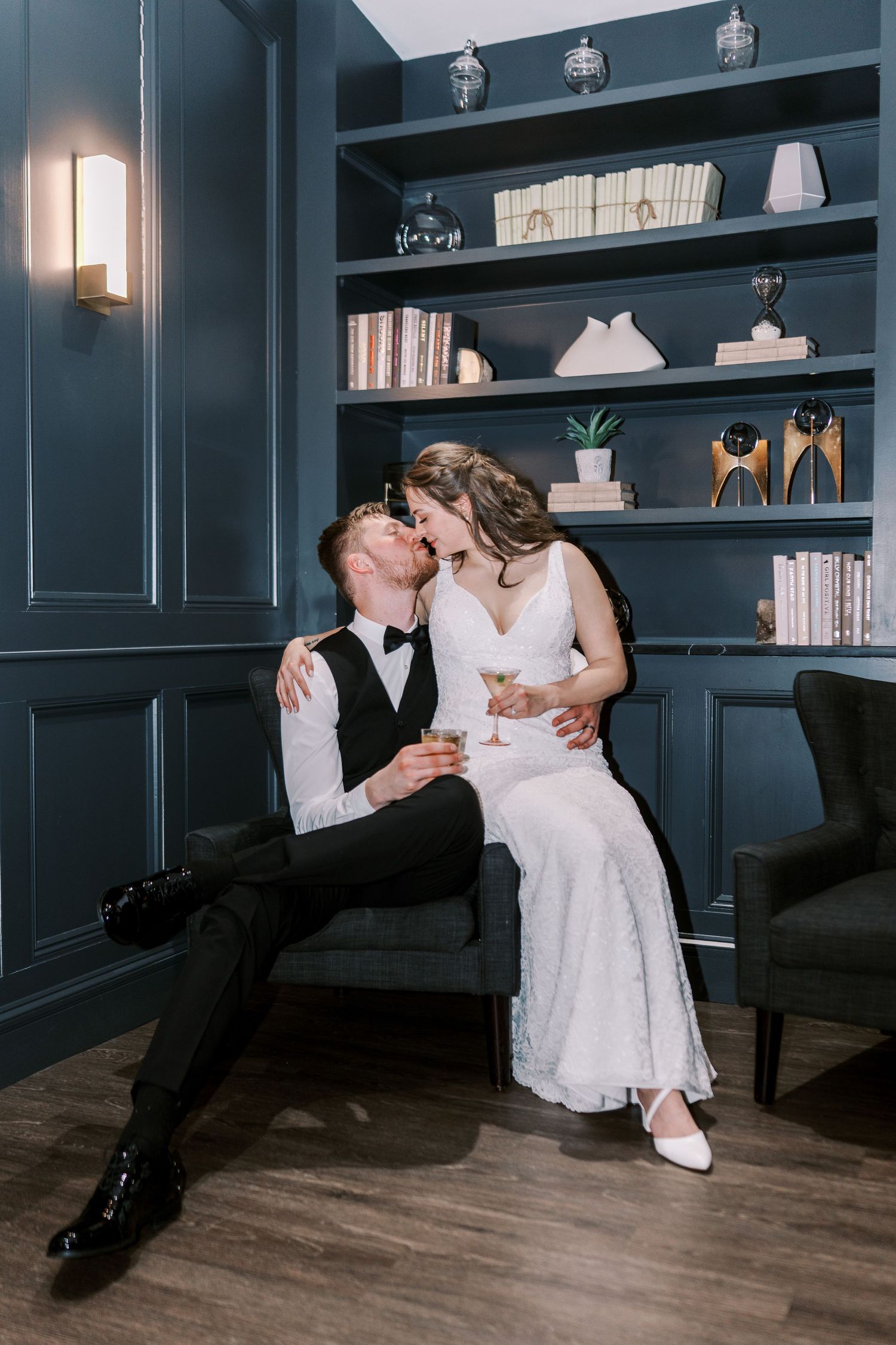 Wedding couple sharing intimate moment in blue room with built-in bookshelves and decor during reception.