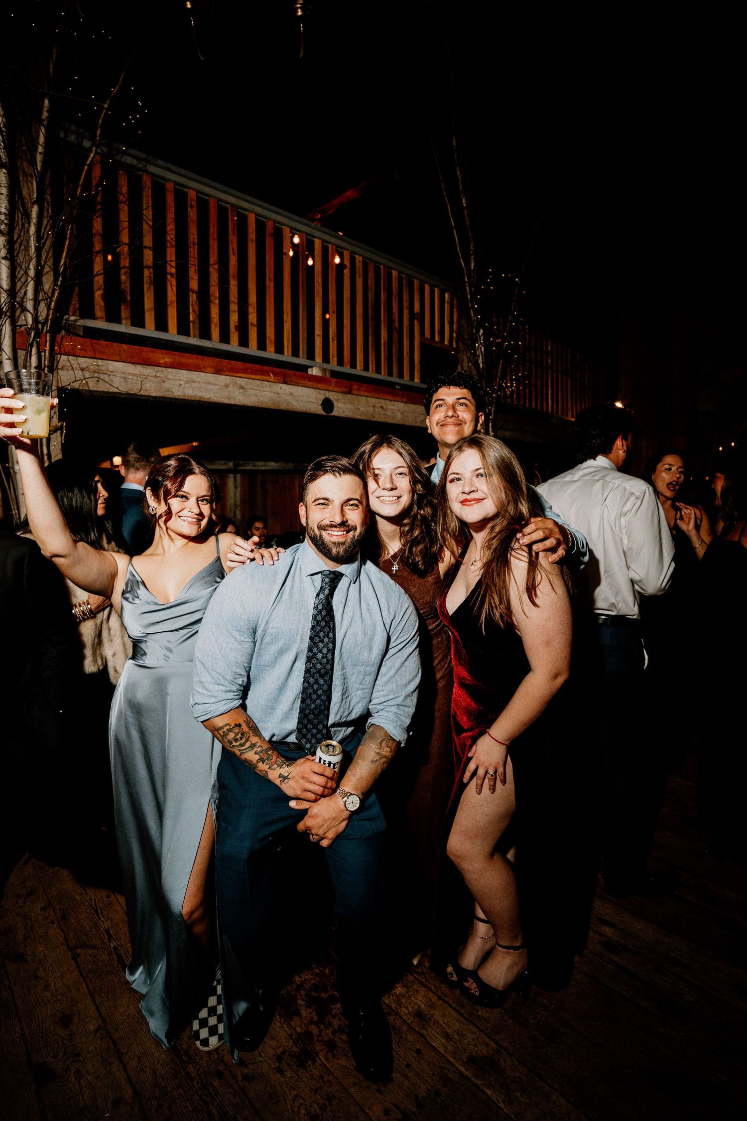 People dancing and having fun at a dimly lit party venue with wooden walls and beams.