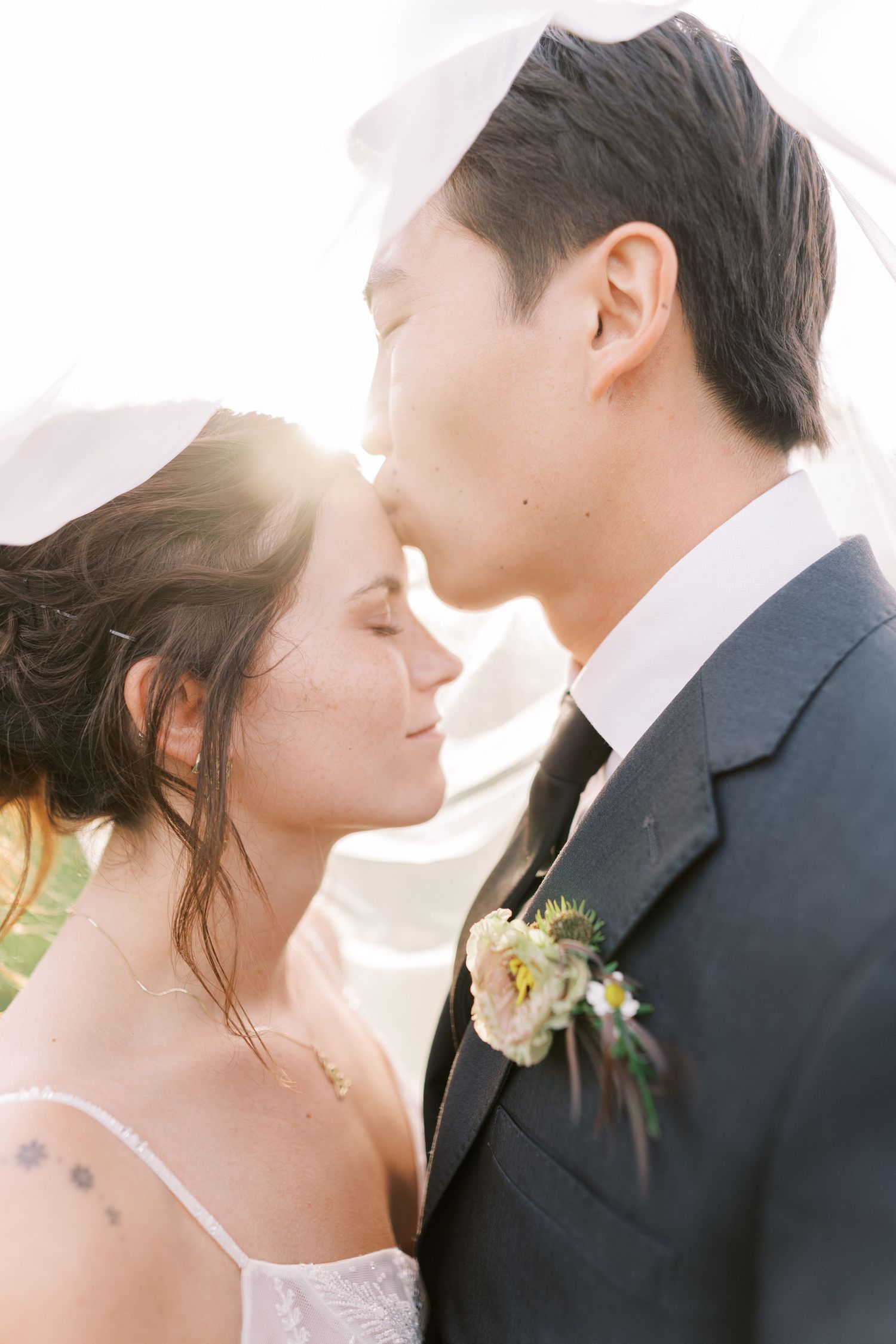 Romantic sunlit close-up portraits of couple in wedding attire.