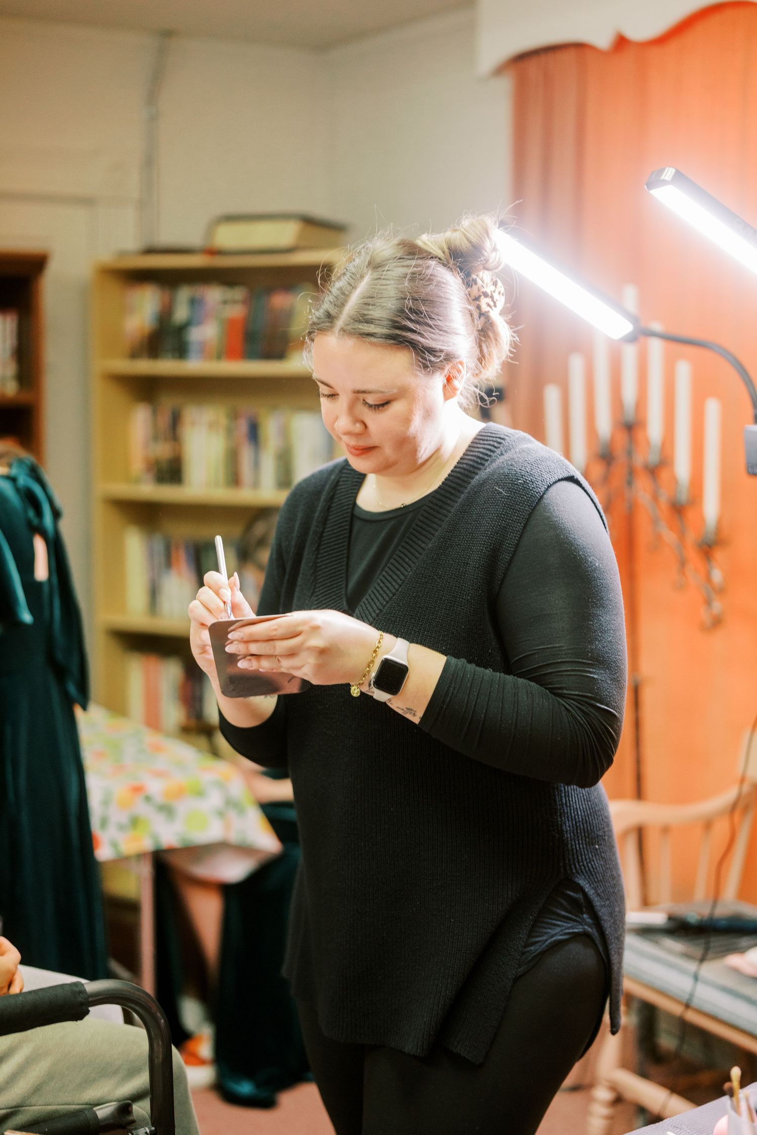 A person in black clothing examines small details in a series of candid preparation shots.
