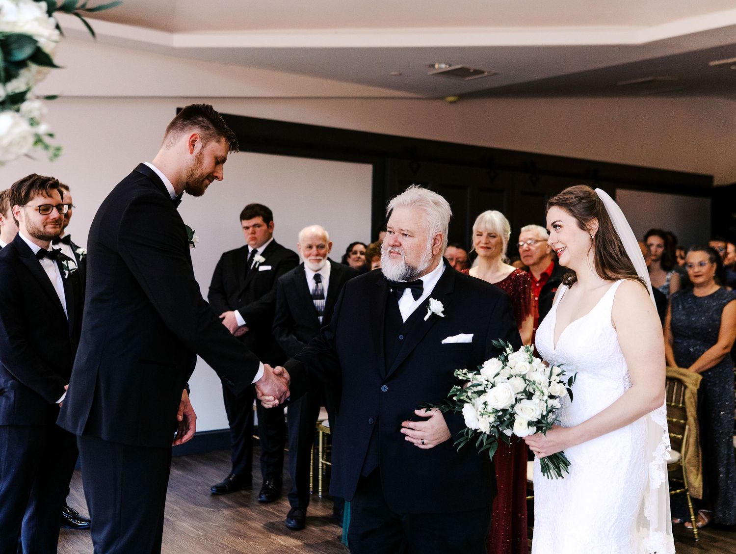 Emotional wedding ceremony moment with guests watching in a modern venue.