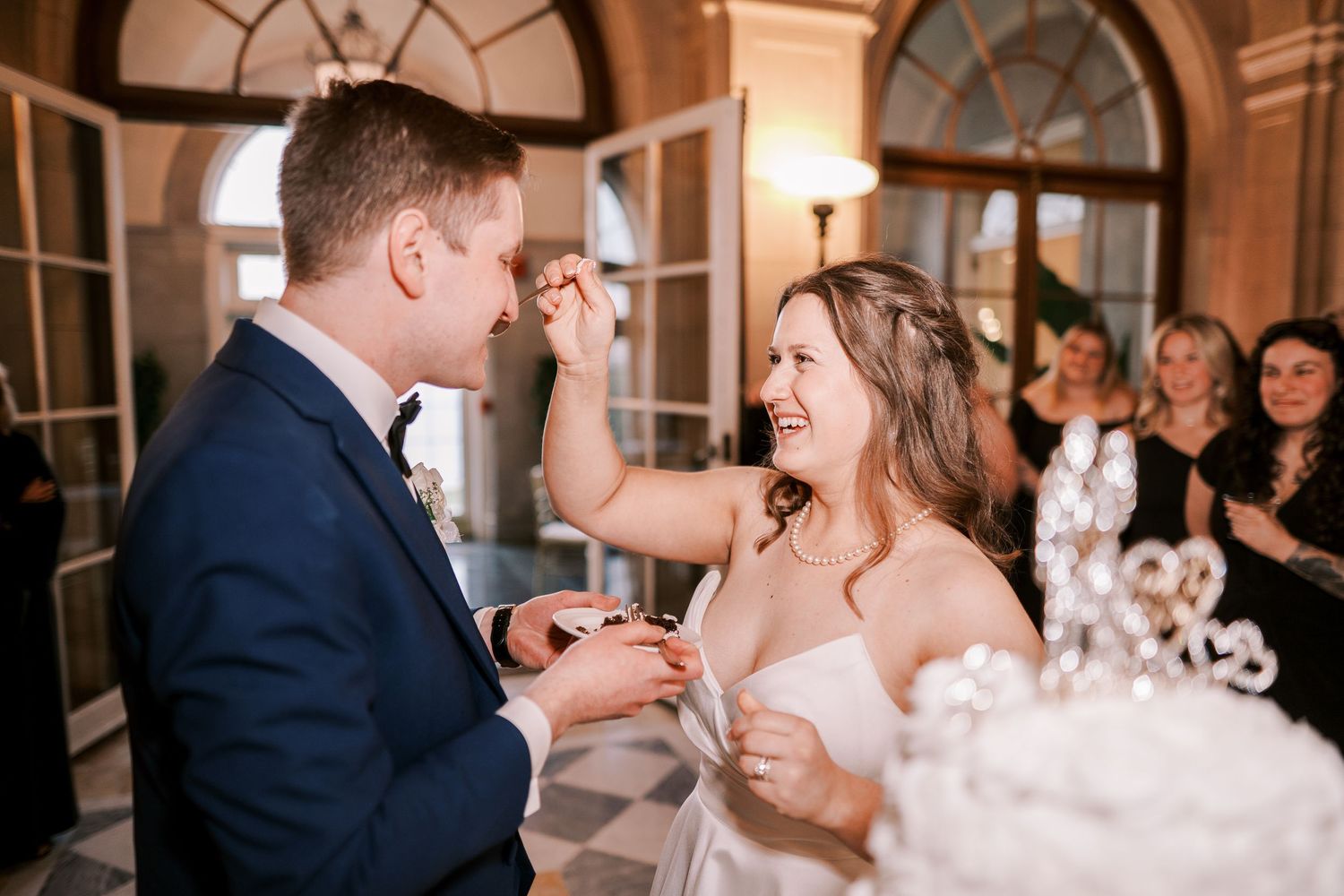 Wedding celebration in an elegant venue with arched windows and soft lighting.