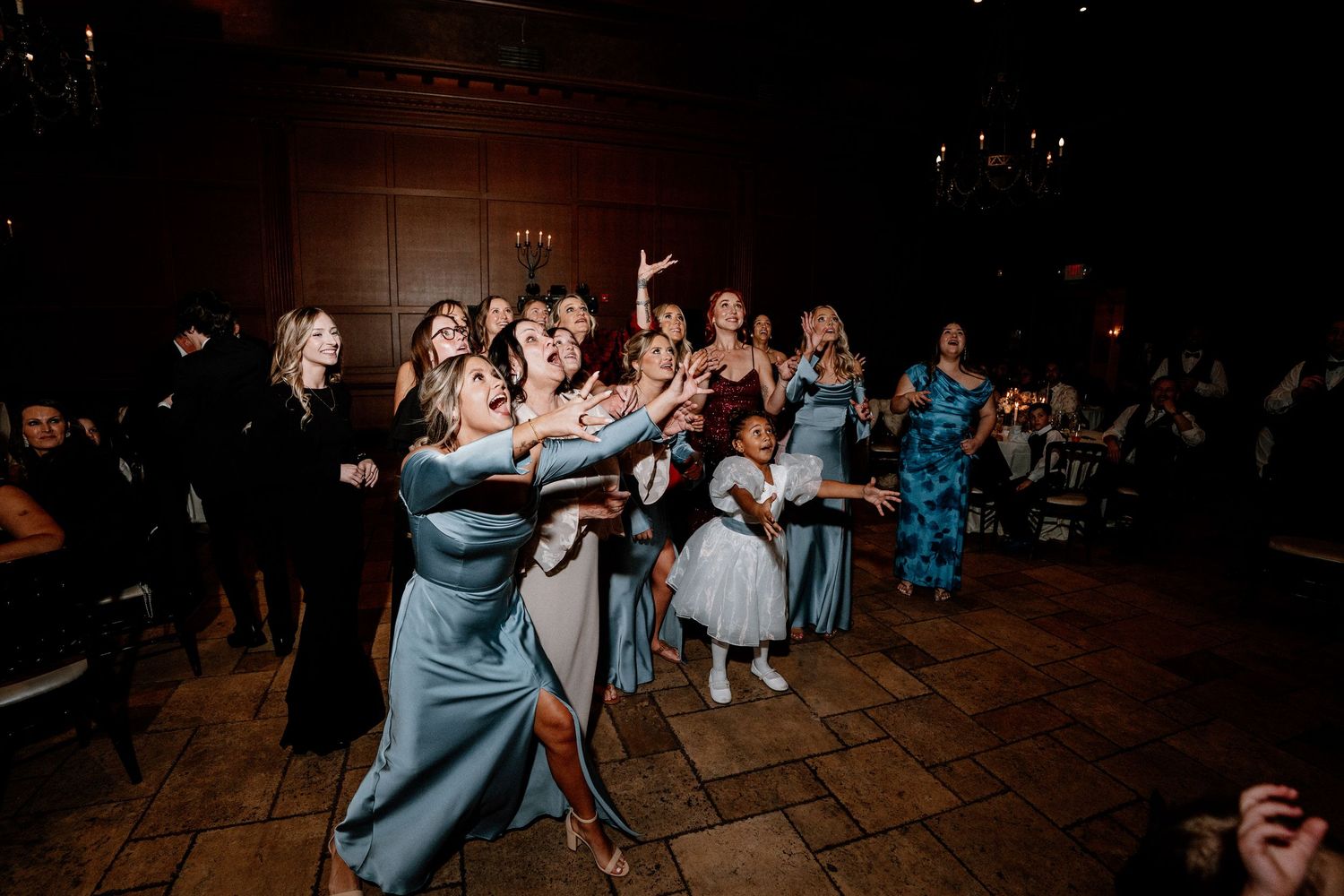 Wedding guests dance and celebrate together on a rustic wooden dance floor at an evening reception.