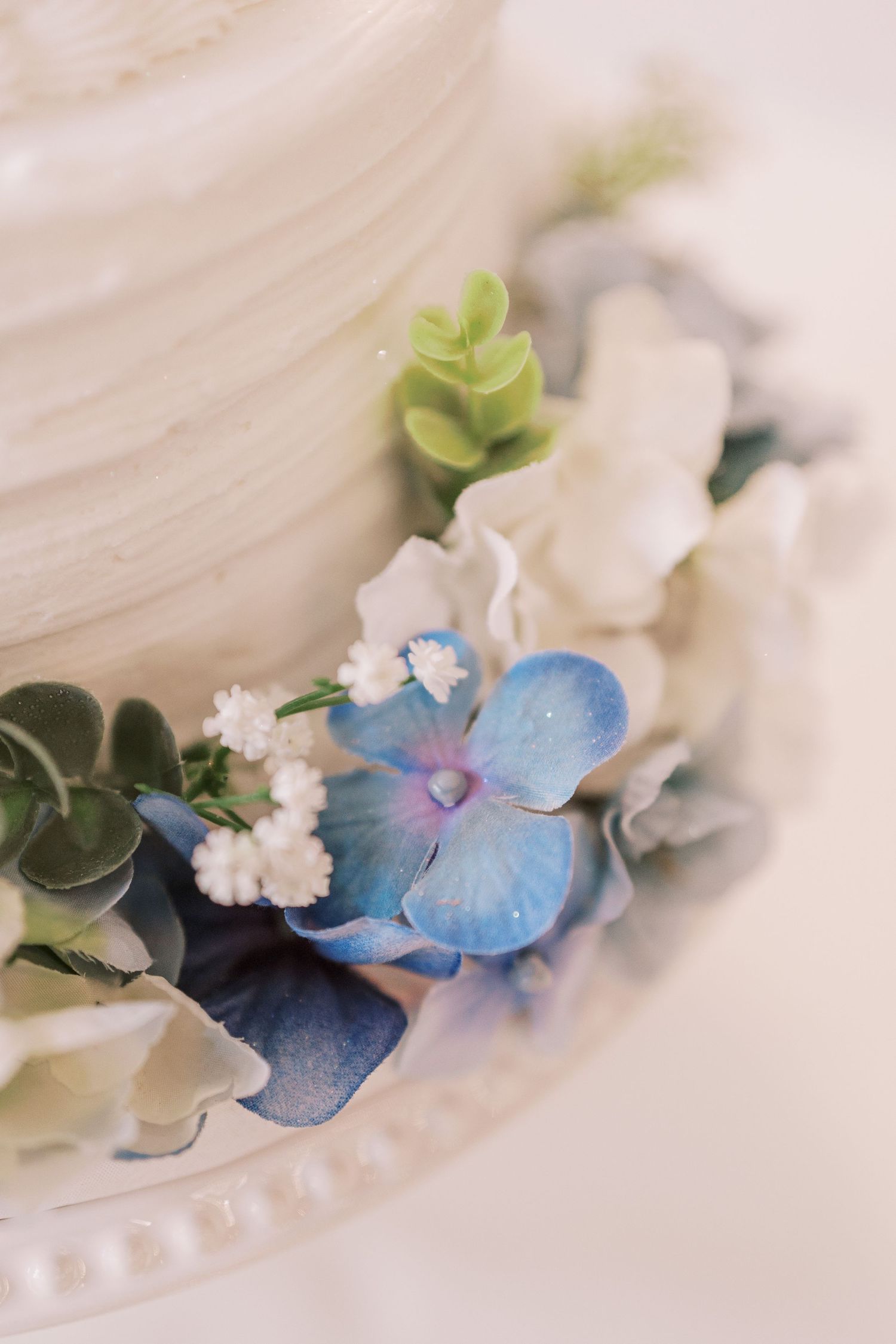 Delicate blue hydrangea and white floral hair accessories arranged on white fabric with soft natural lighting.