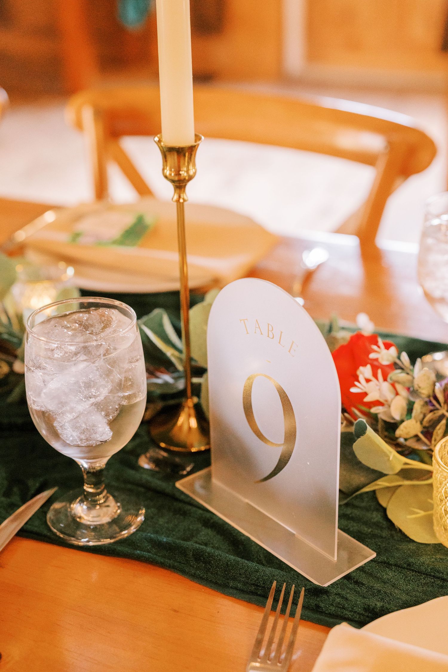 Elegant table setting with white candles, green velvet runner, and crystal glassware for a formal dining event.