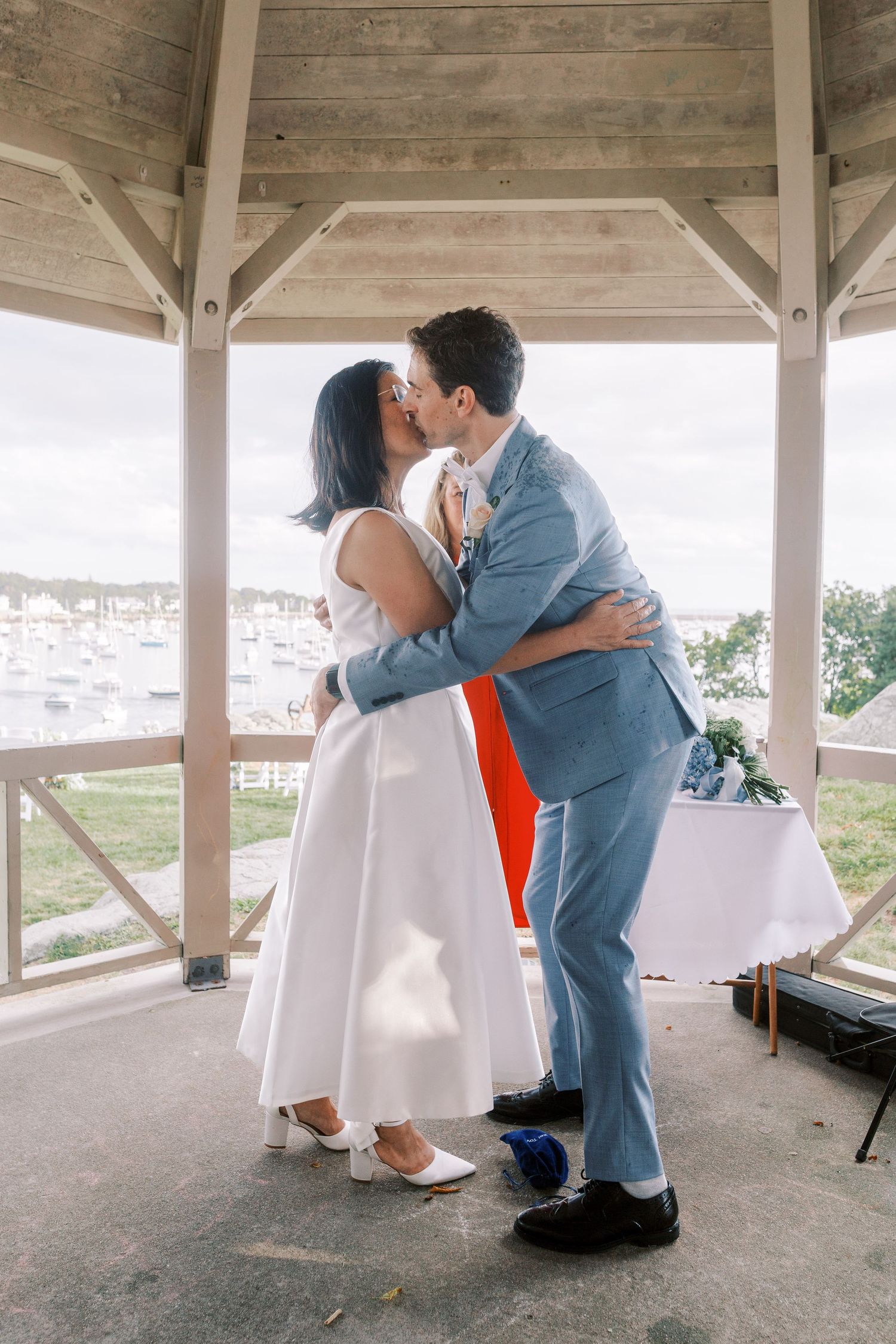 Couple shares intimate moments during first look photos under rustic wooden shelter.