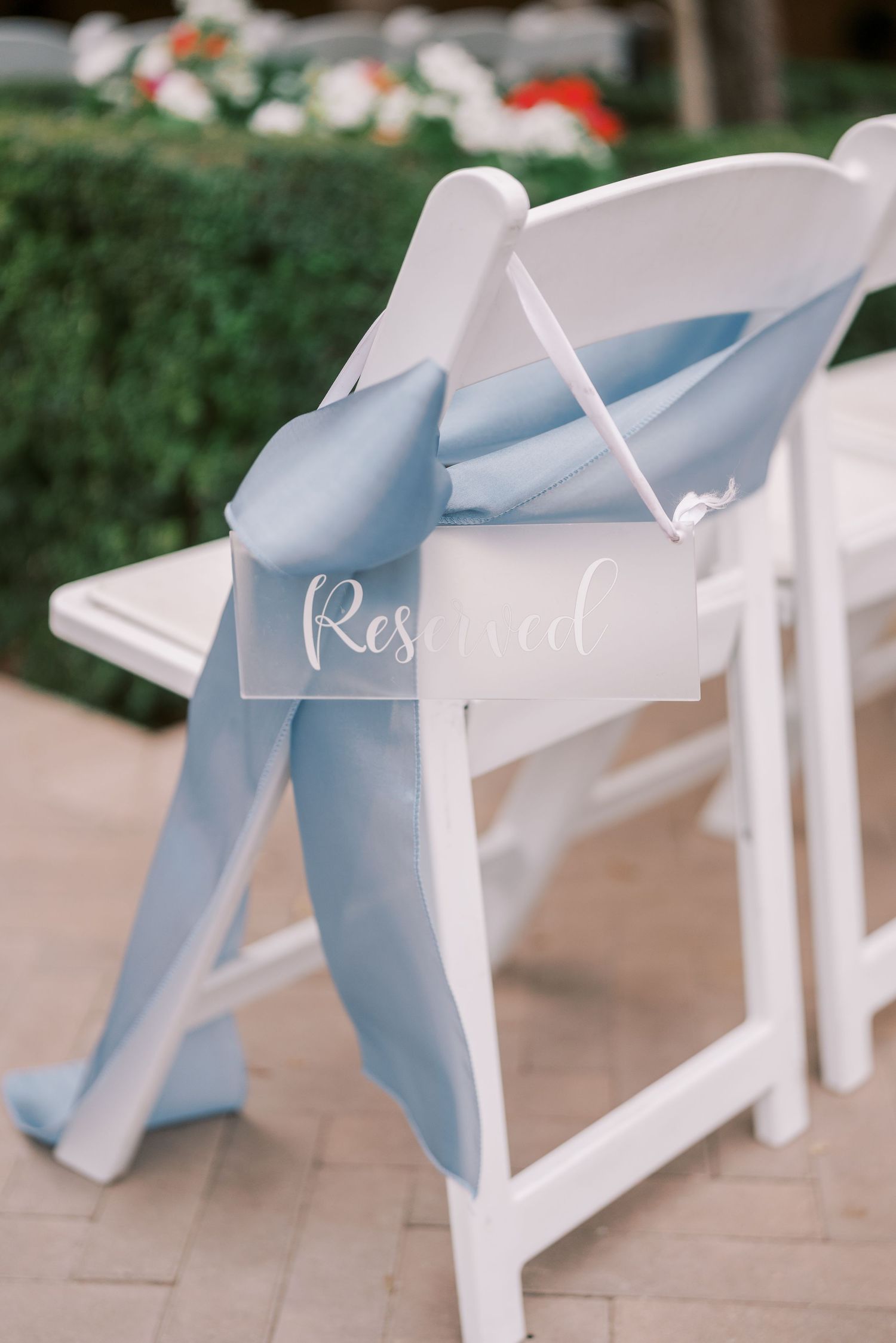 Light blue ribbons tied elegantly around white ceremony chairs create a soft, romantic wedding decor detail.
