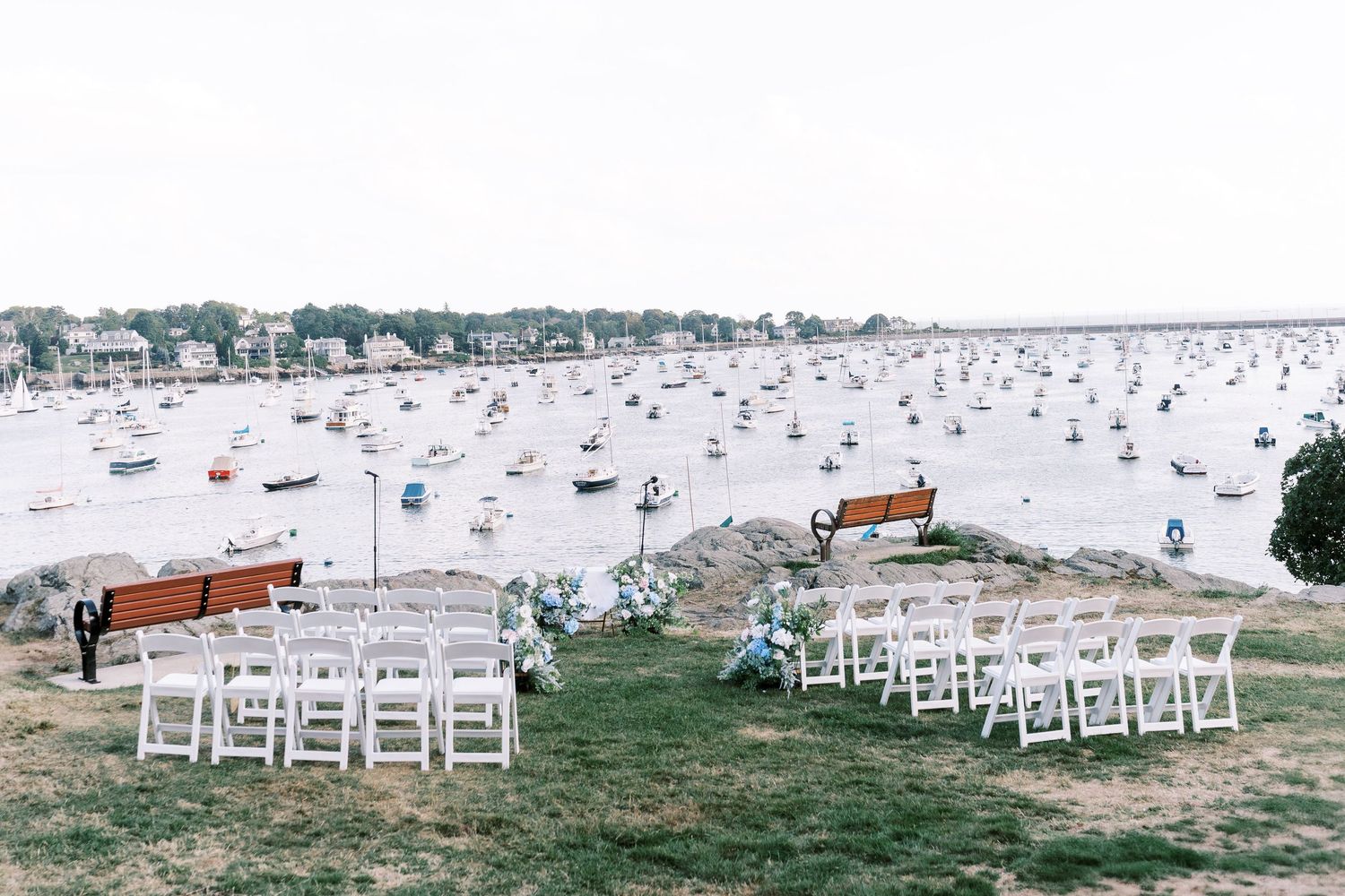 Rows of white chairs set up on grassy waterfront for outdoor wedding ceremony.