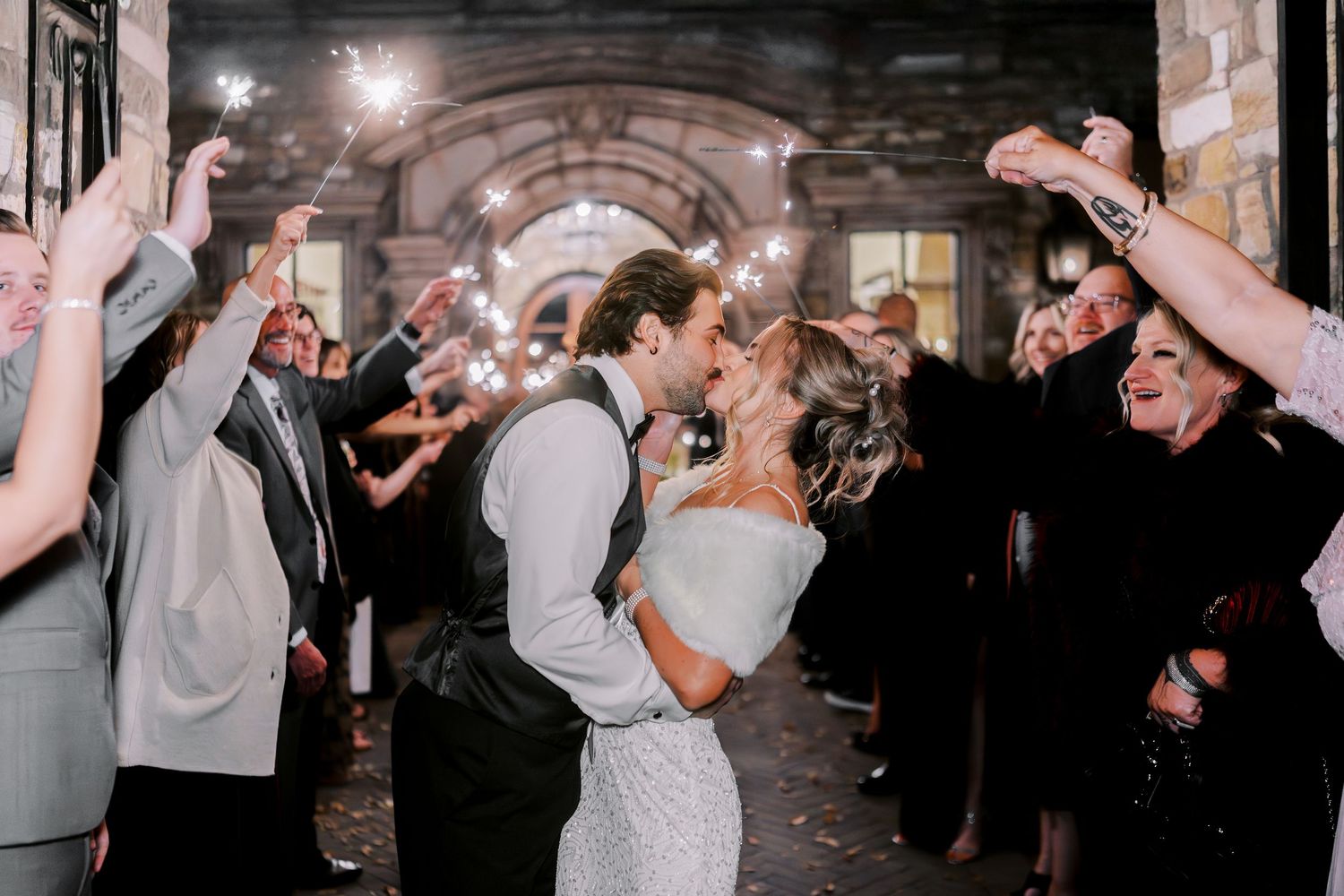 Wedding guests form a joyful dance circle on the reception floor during a celebration.