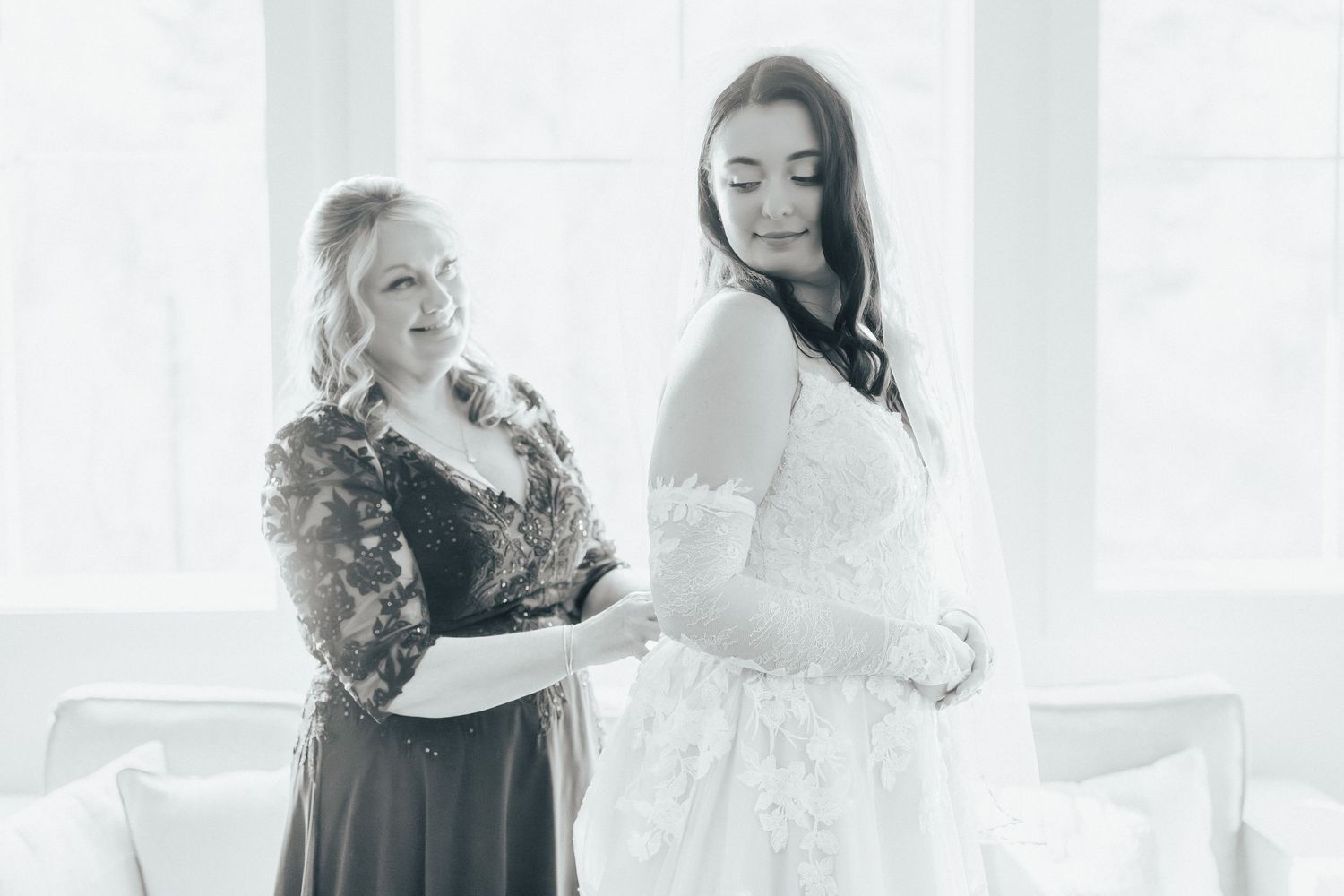 A group of people in white dresses share joyful moments during a wedding preparation.