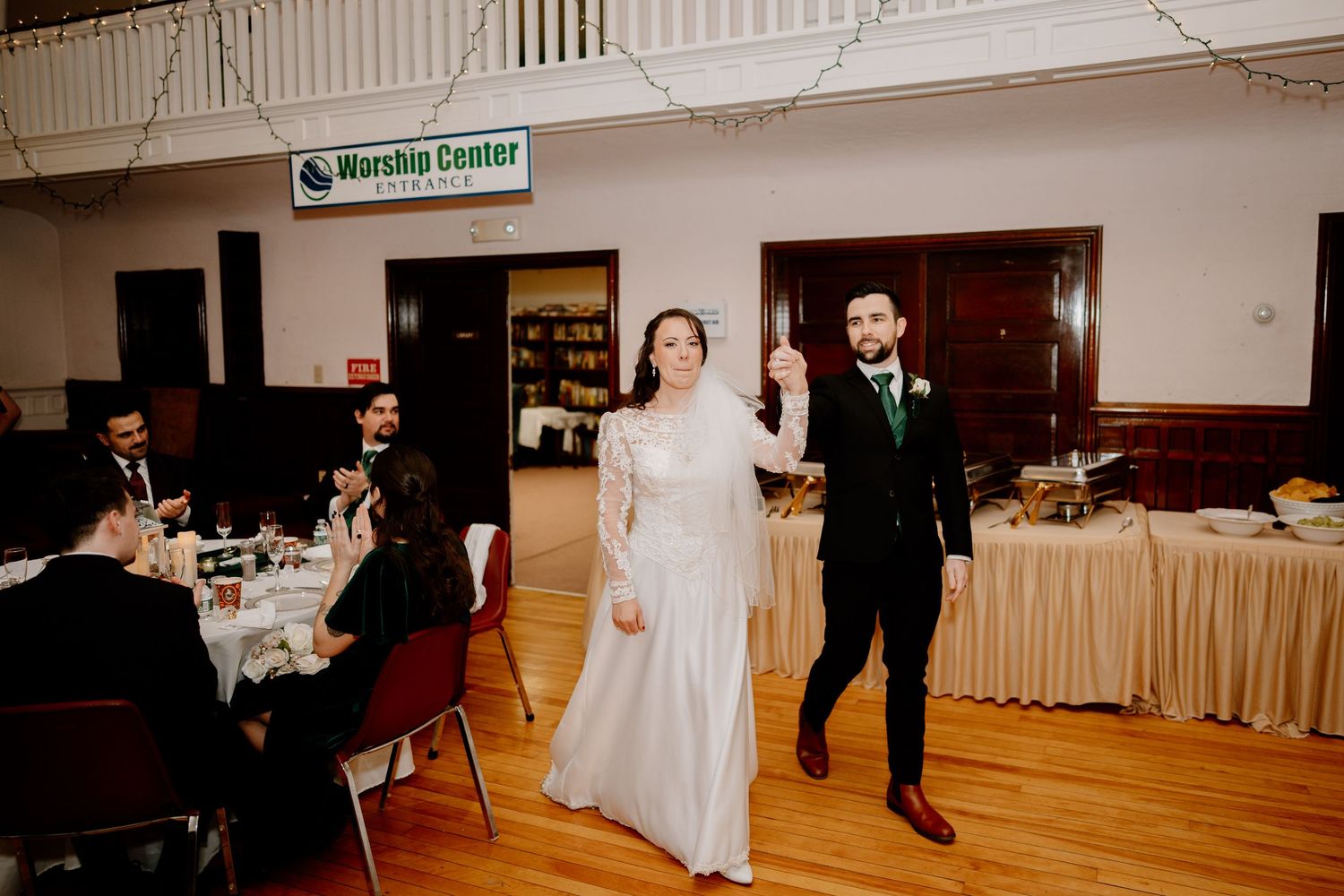 Wedding couple making grand entrance at reception in community center hall.