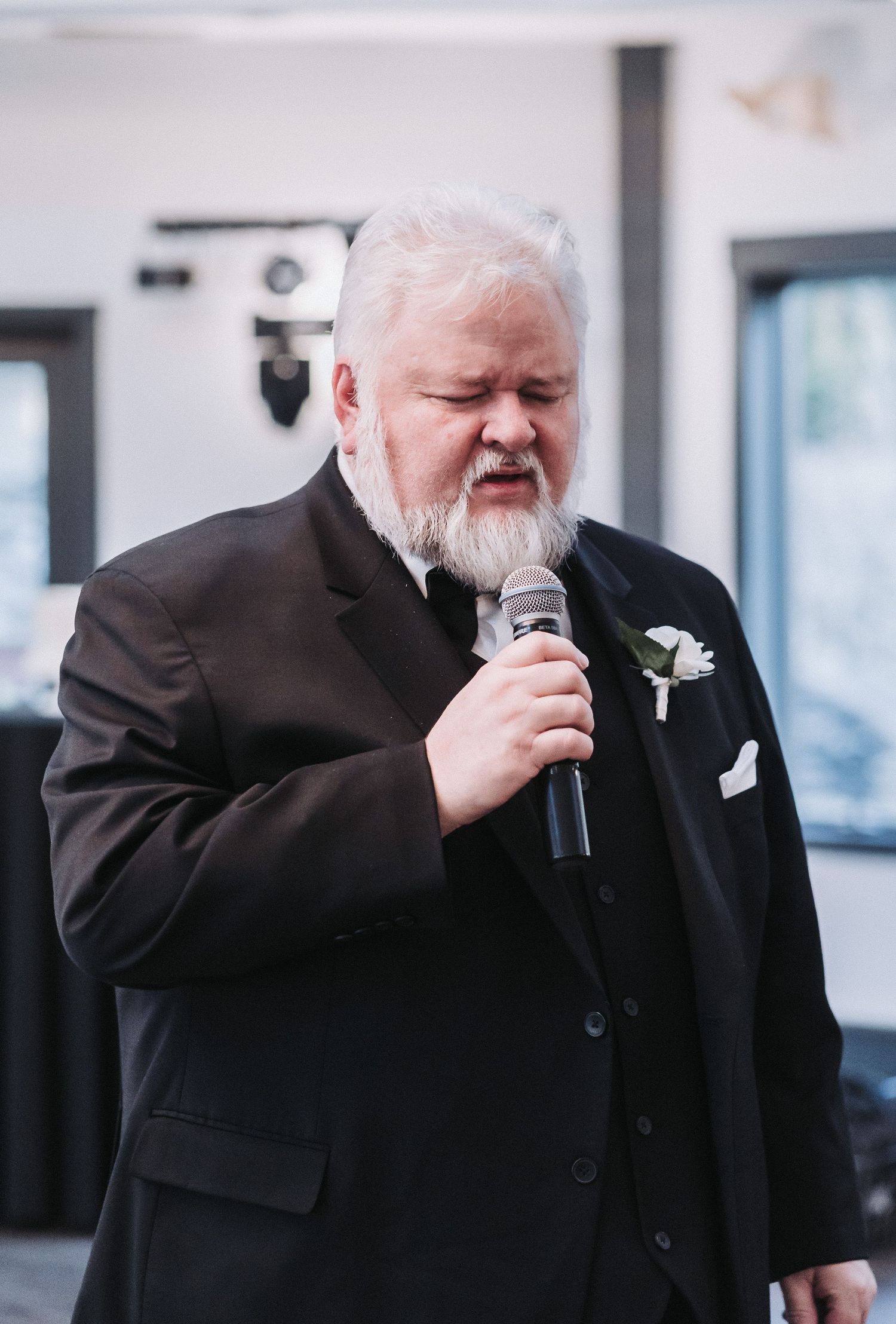 Person in formal attire delivering an emotional speech during a wedding reception.